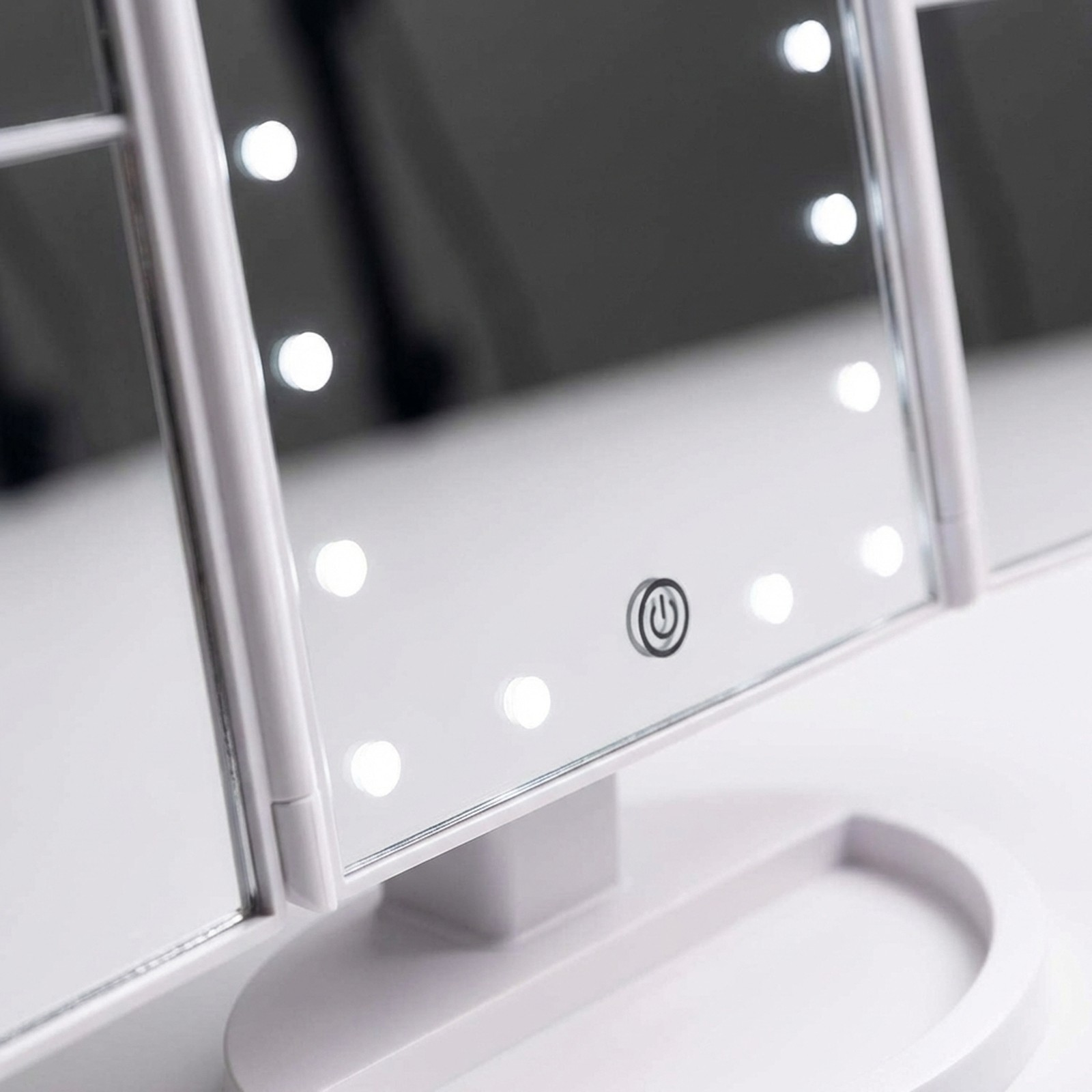 Uno specchio per il trucco bianco pieghevole in tre parti con luci LED.