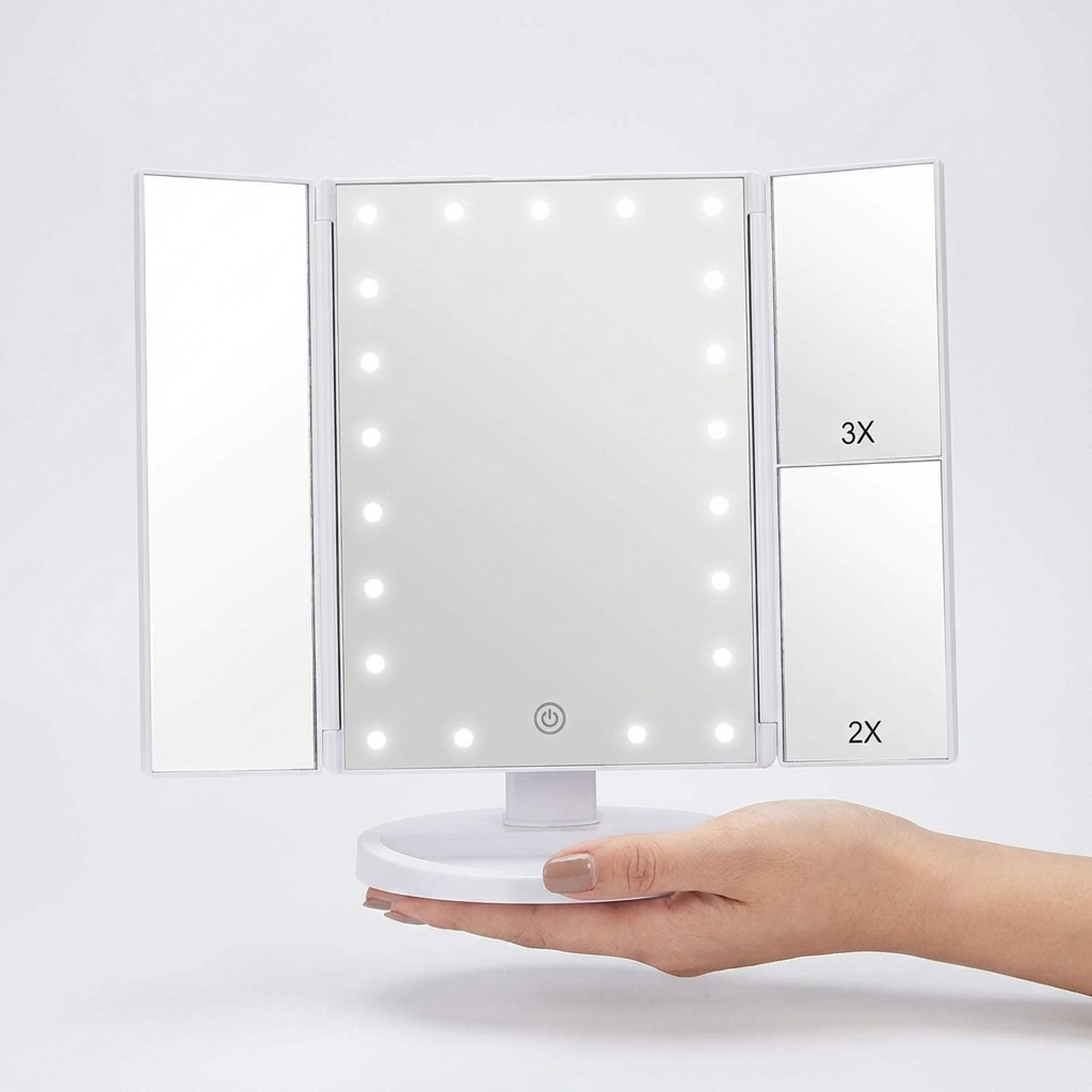 Uno specchio per il trucco bianco pieghevole con luci a LED è tenuto da una mano.