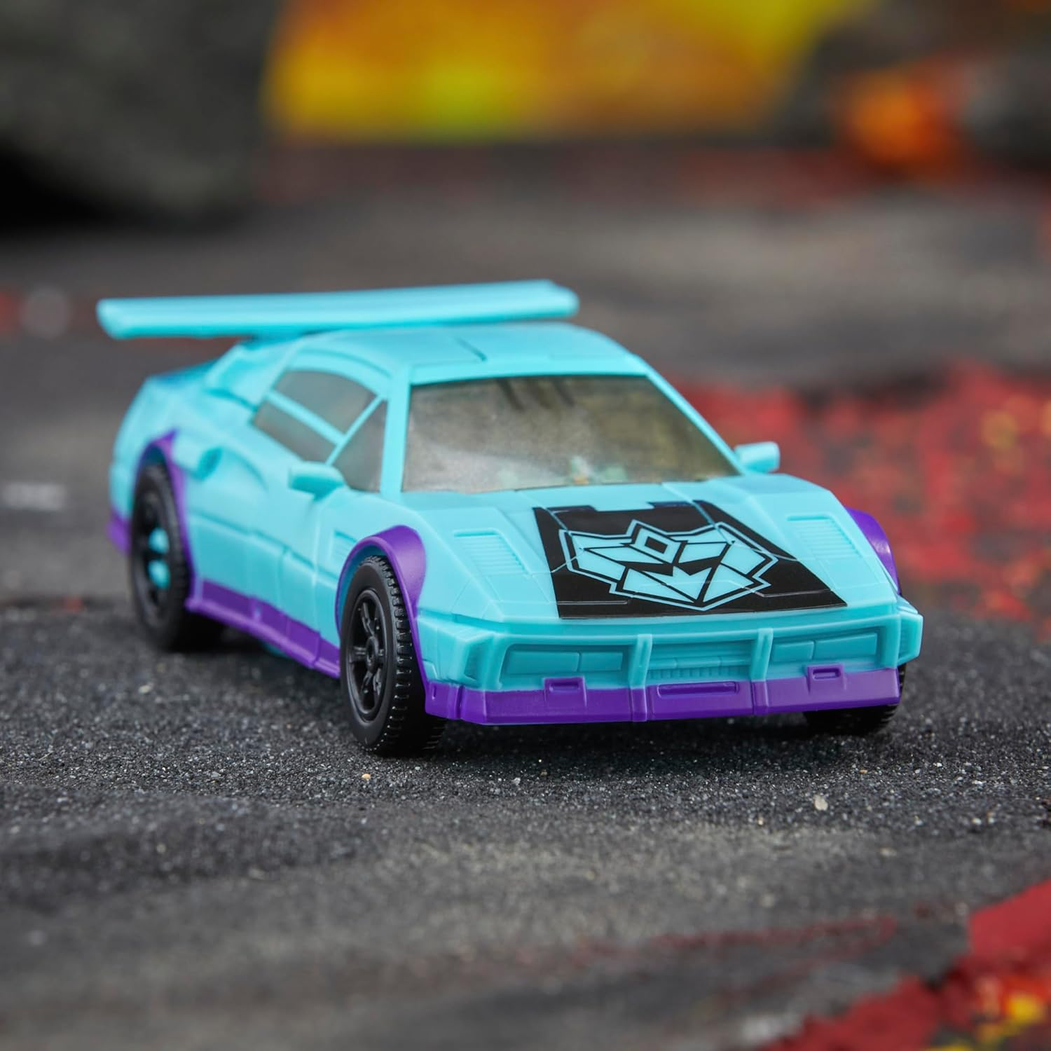 Ein hellblauer Spielzeugsportwagen mit lila Akzenten und einem schwarzen Abzeichen auf der Motorhaube.