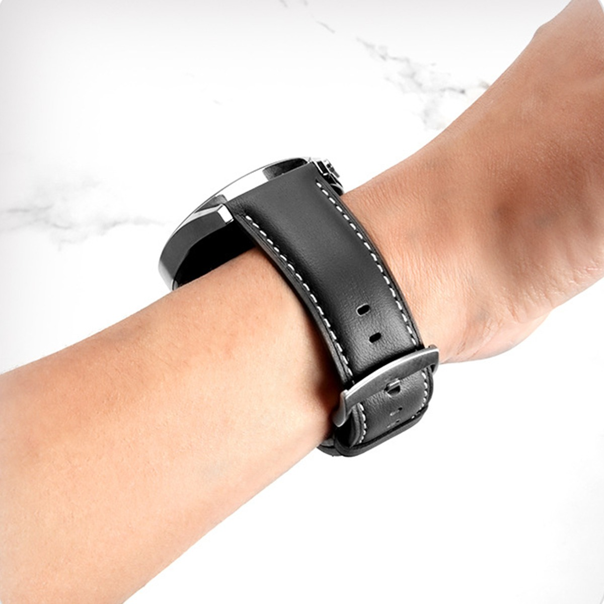 Ein schwarzes Lederarmband mit weißen Nähten, das an einem Arm befestigt ist.