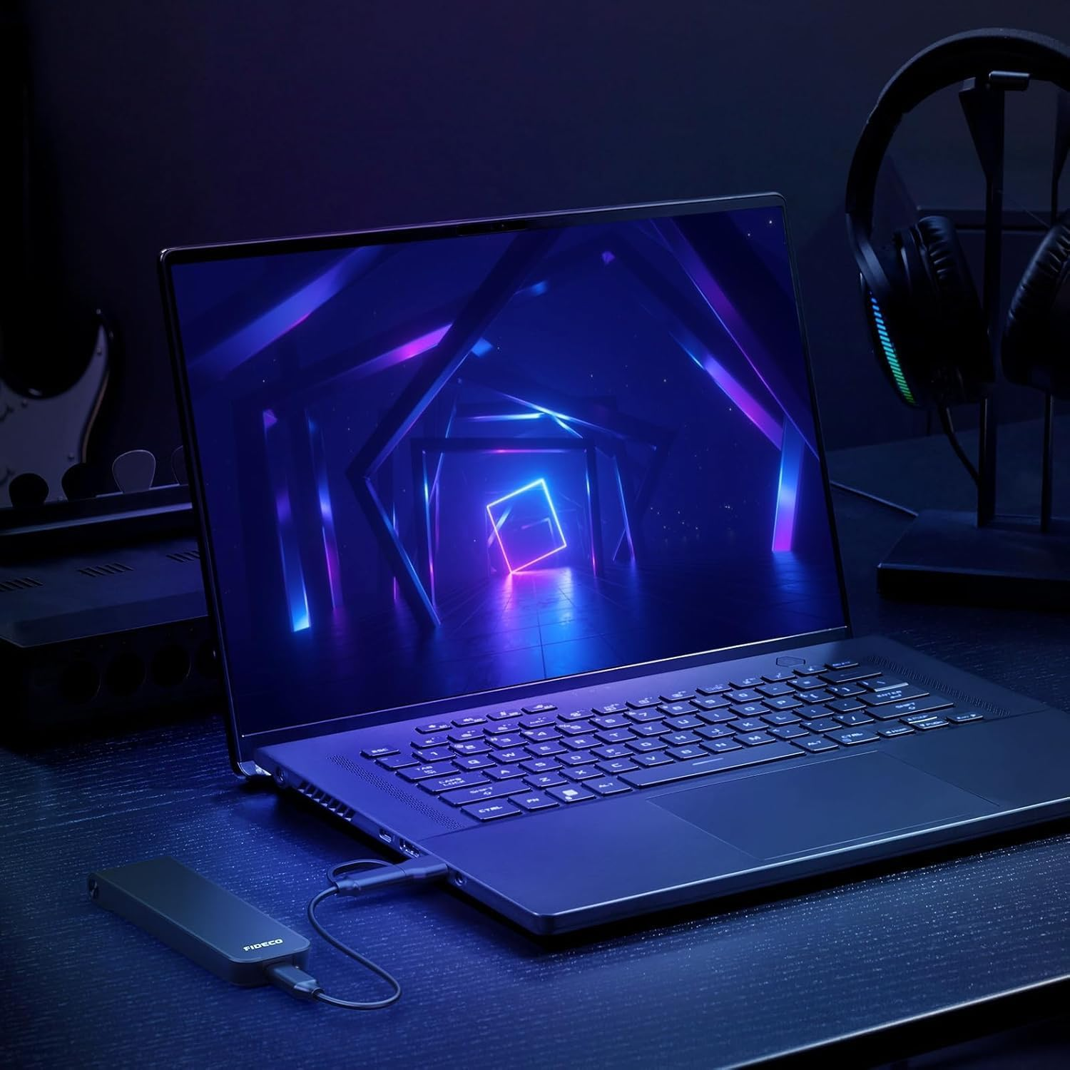 Ein Laptop mit Neon-Grafik, Festplatte, Kopfhörern und Gitarre.