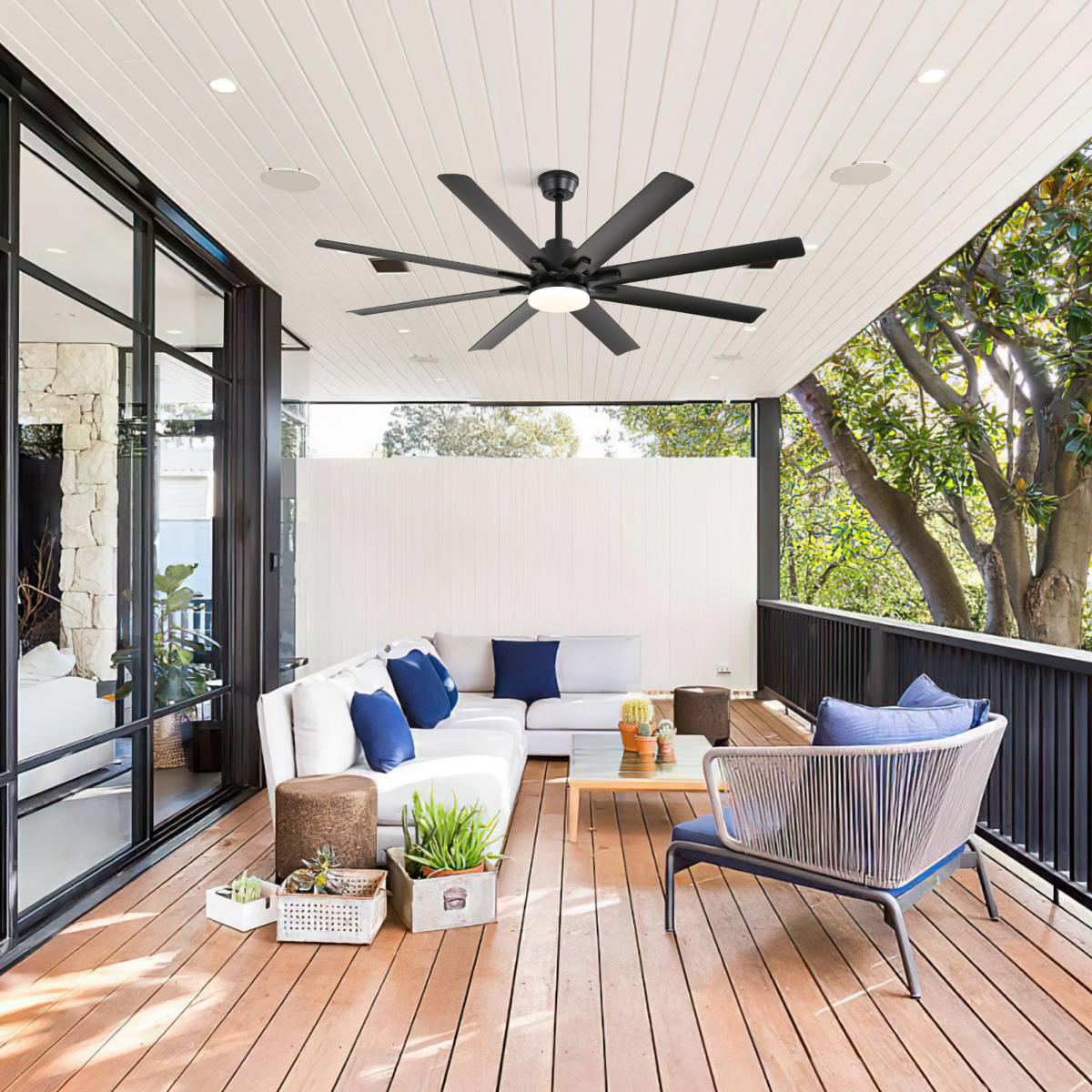 Eine überdachte Terrasse mit Holzfußboden, einem weißen Sofa, Sesseln und einem Deckenventilator.