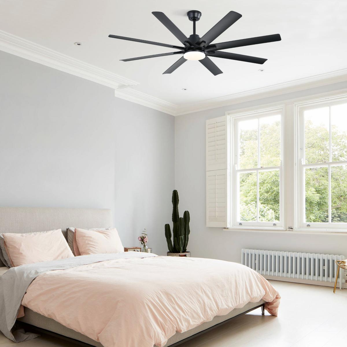 Ein modernes Schlafzimmer mit einer großen rosa Bettdecke, zwei Kissen, einem hohen Kaktus und einem schwarzen Deckenventilator.