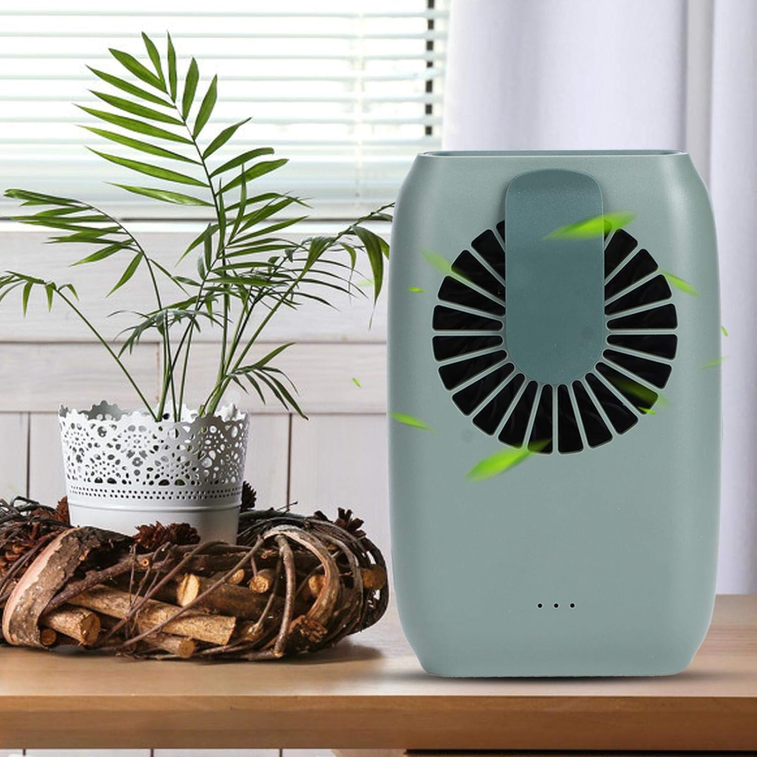 Ein grüner Ventilator mit Lüftungsschlitzen neben einer Pflanze in einem Topf.