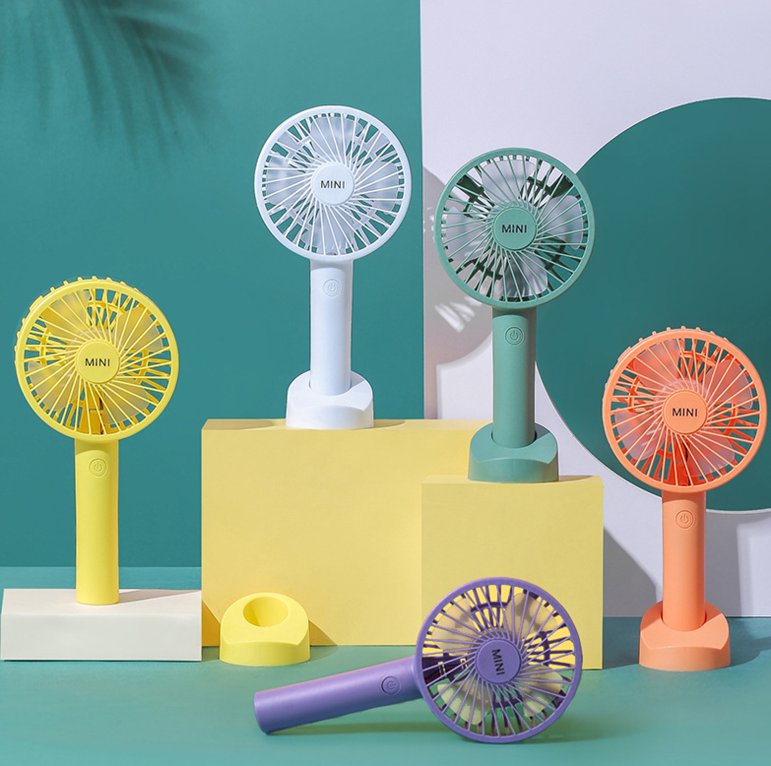 Fünf Mini-Ventilatoren in Gelb, Weiß, Grün, Orange und Lila auf bunten Podesten.