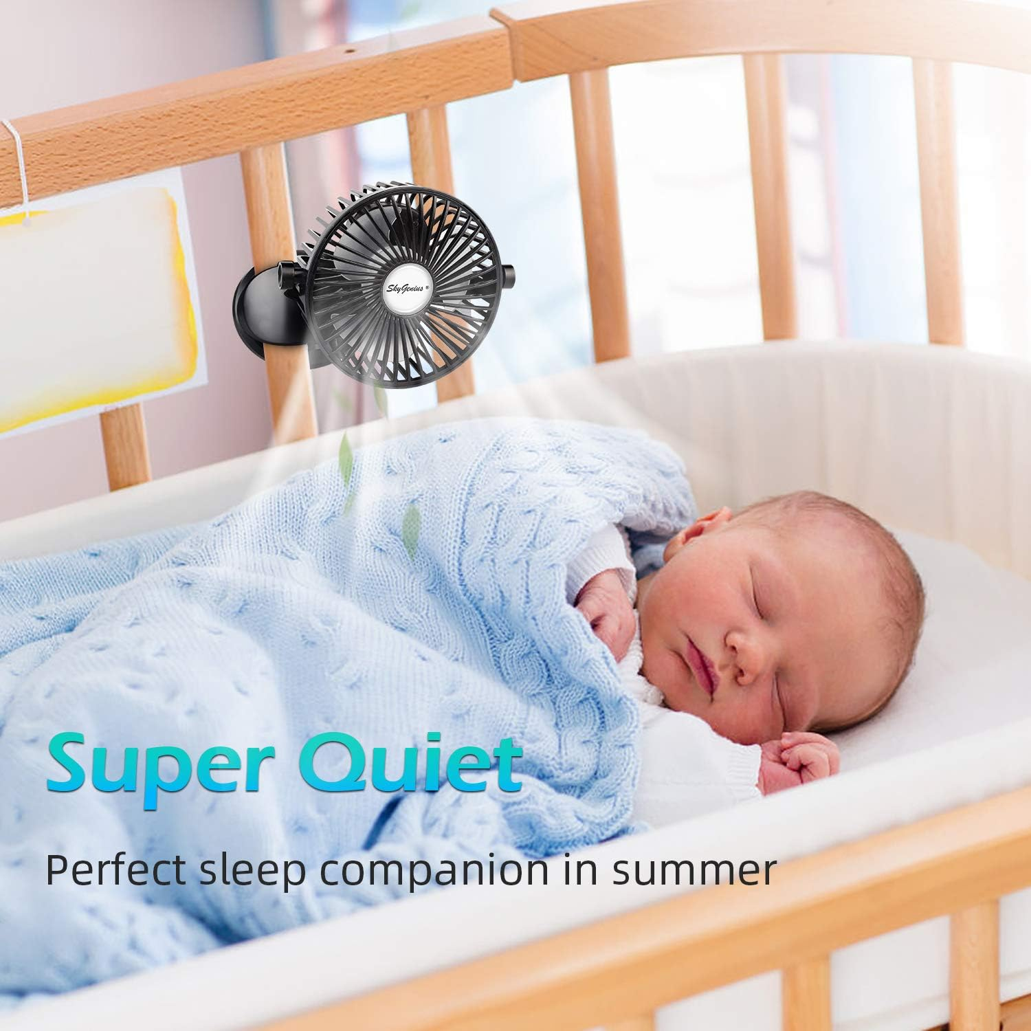 Ein kleiner schwarzer Ventilator an einem Babybett, der einen schlafenden Säugling anbläst.