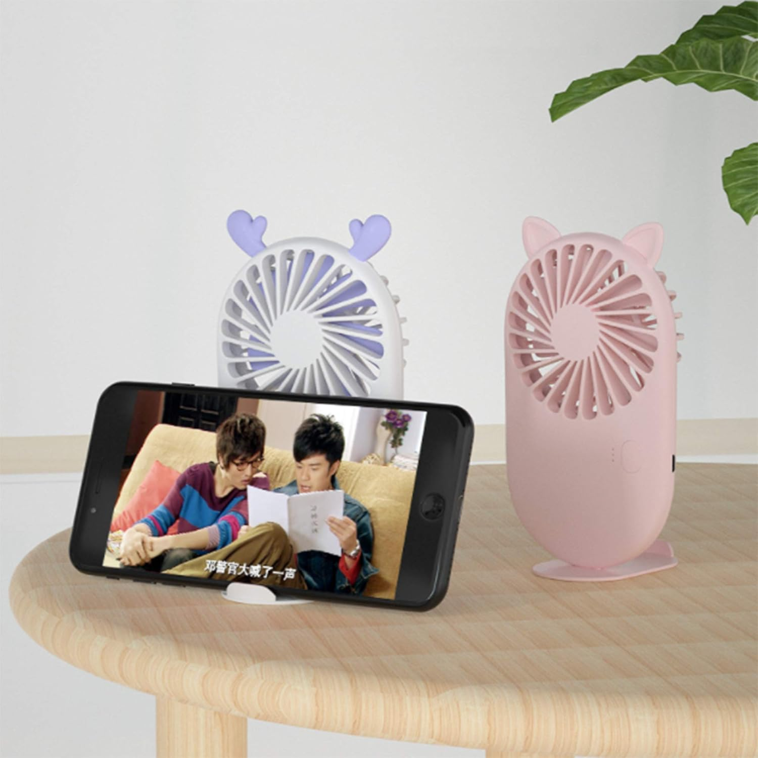 Zwei niedliche Lüfter auf einem Holztisch mit einem Handy, das zwei Männer zeigt.