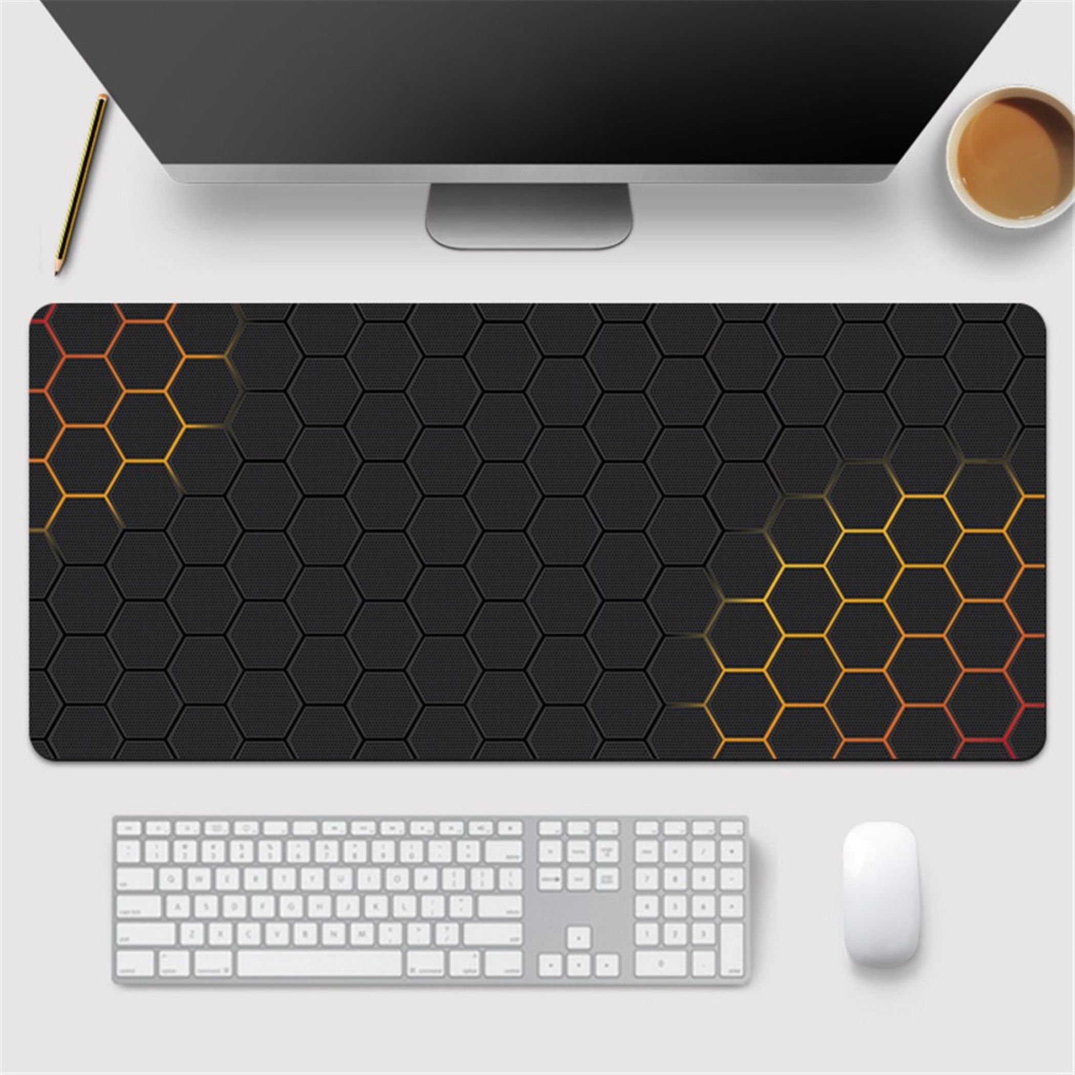 Ein Schreibtisch mit einem Monitor, Tastatur, Maus, Kaffee und einer Mausunterlage mit Wabendesign.