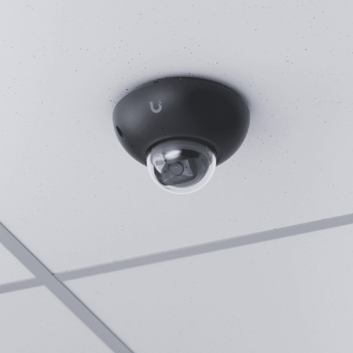 Eine dunkle Überwachungskamera mit Kuppel ist an einer abgehängten Decke montiert.