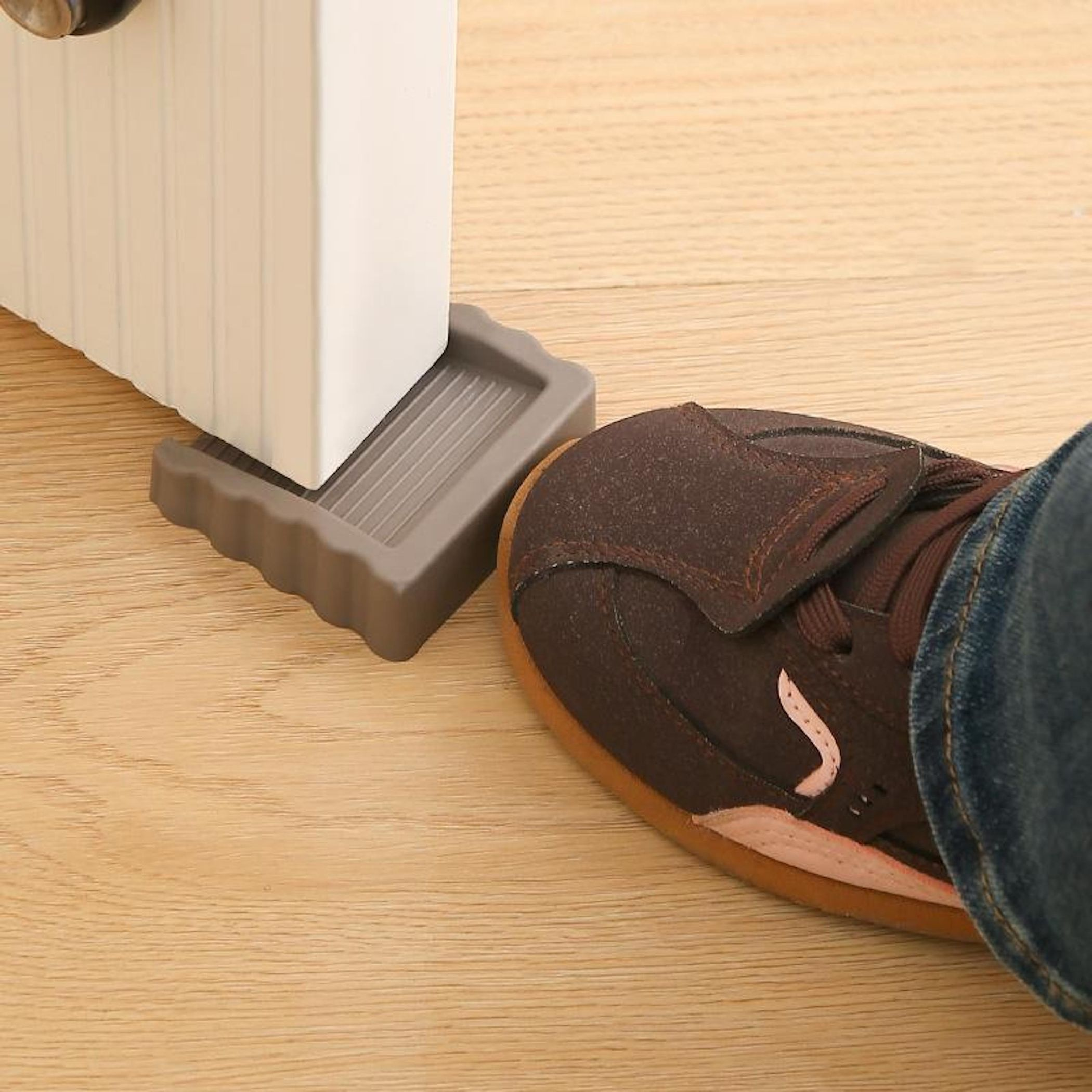 Una scarpa marrone e una porta bianca sollevate su un pavimento in legno.