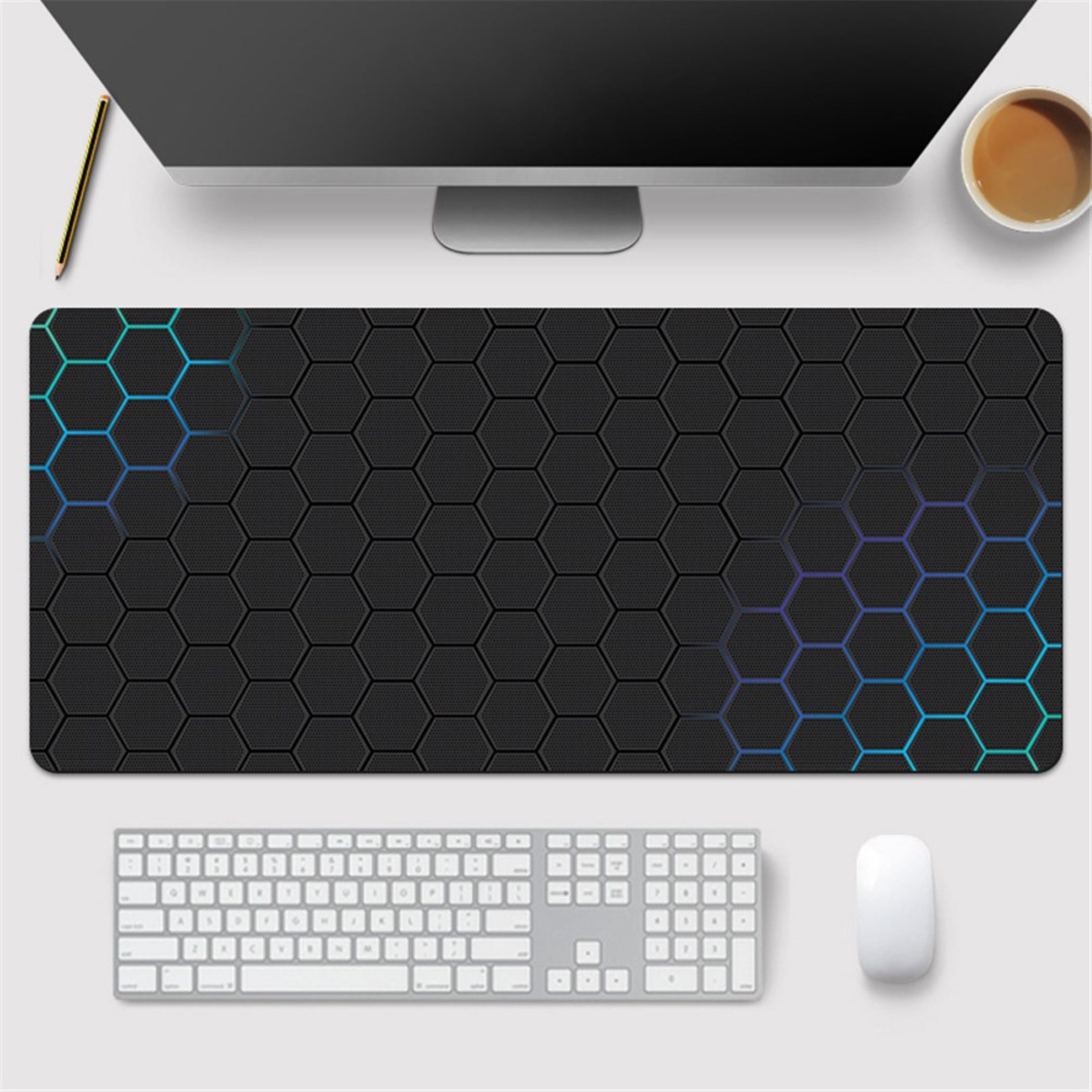 Schwarzer Mauspad mit sechseckigem Muster und blauen Akzenten, Tastatur, Maus, Monitor, Stift, Kaffee.