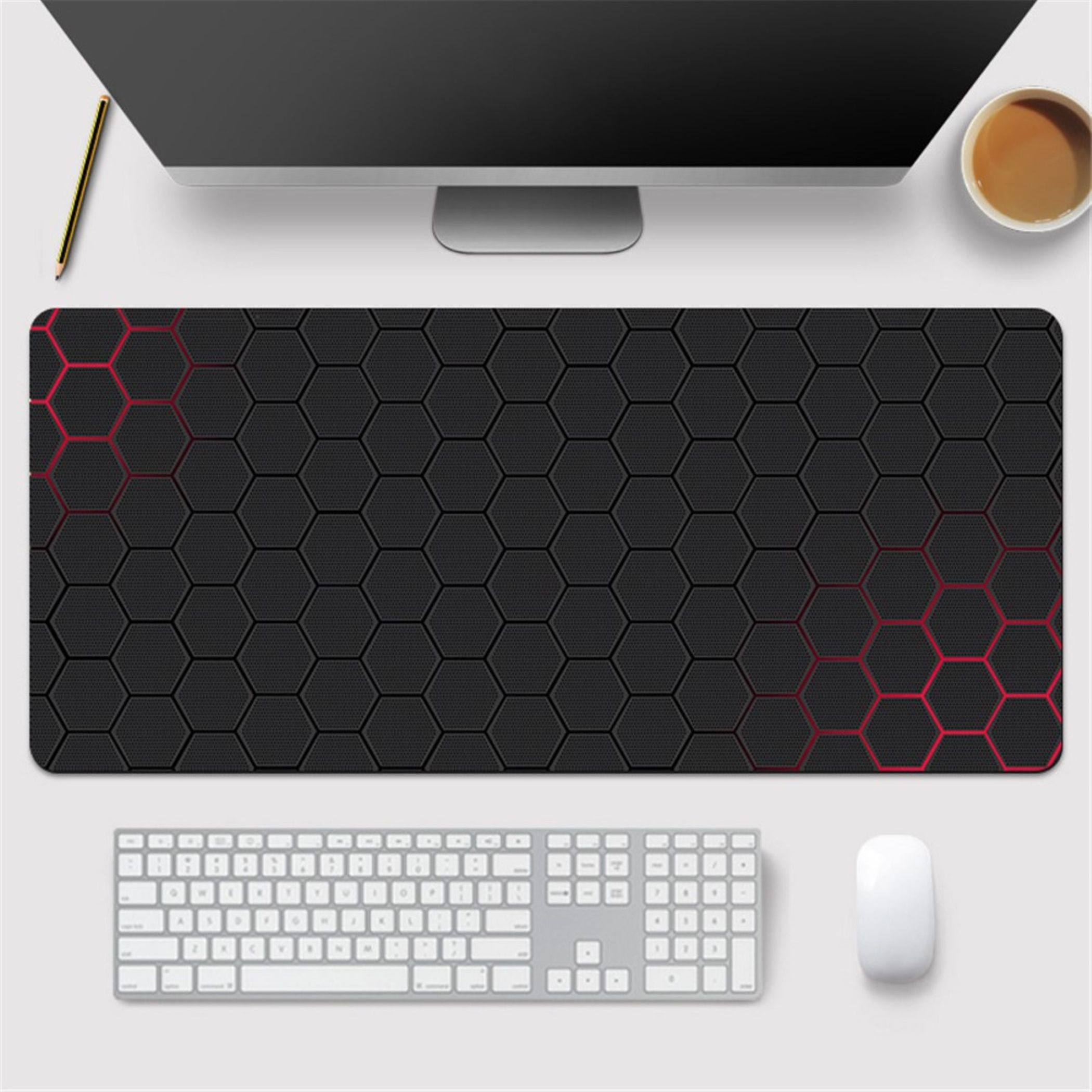 Ein schwarzes, sechseckiges Mauspad mit roten Akzenten steht auf einem Schreibtisch mit Tastatur, Maus, Monitor, Stift u. Kaffee.