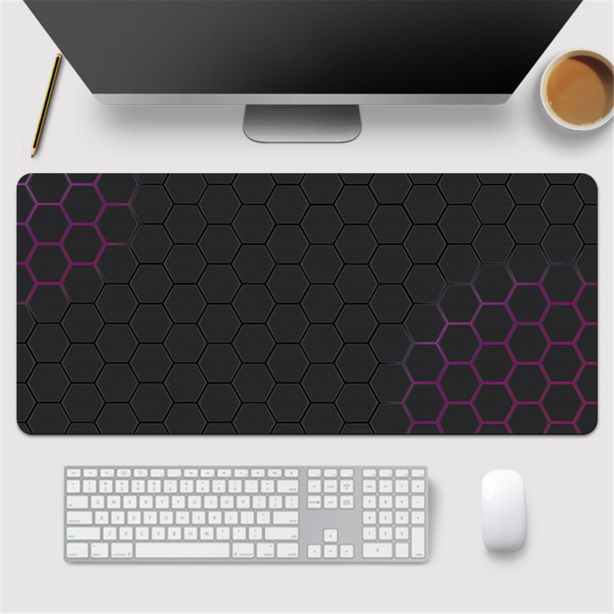 Schwarze Mausmatte mit Hexagonmuster, Tastatur, Maus, Monitor und Kaffee.