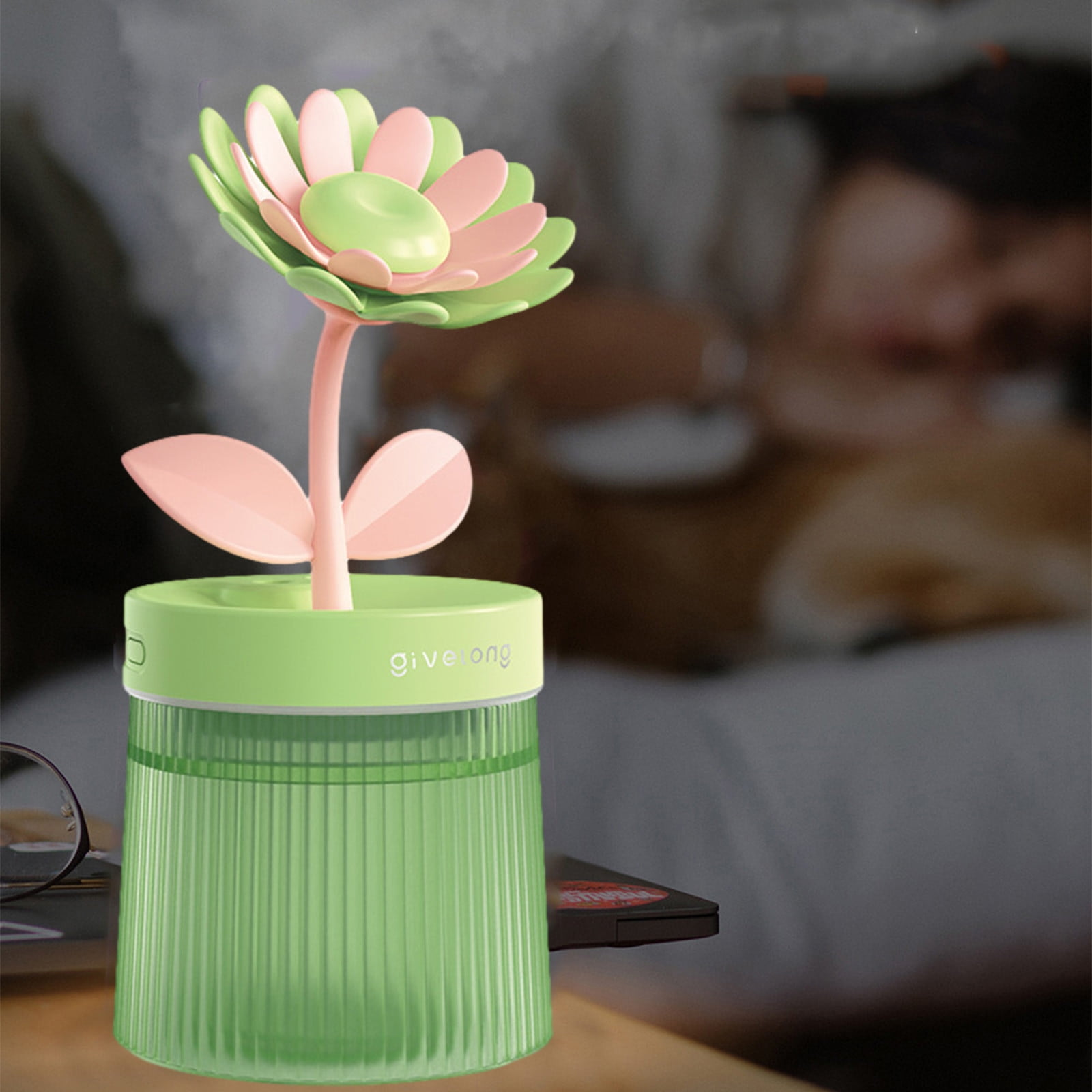 Grüner Vernebler mit rosa und grüner Blume. Im Hintergrund schläft eine Person.
