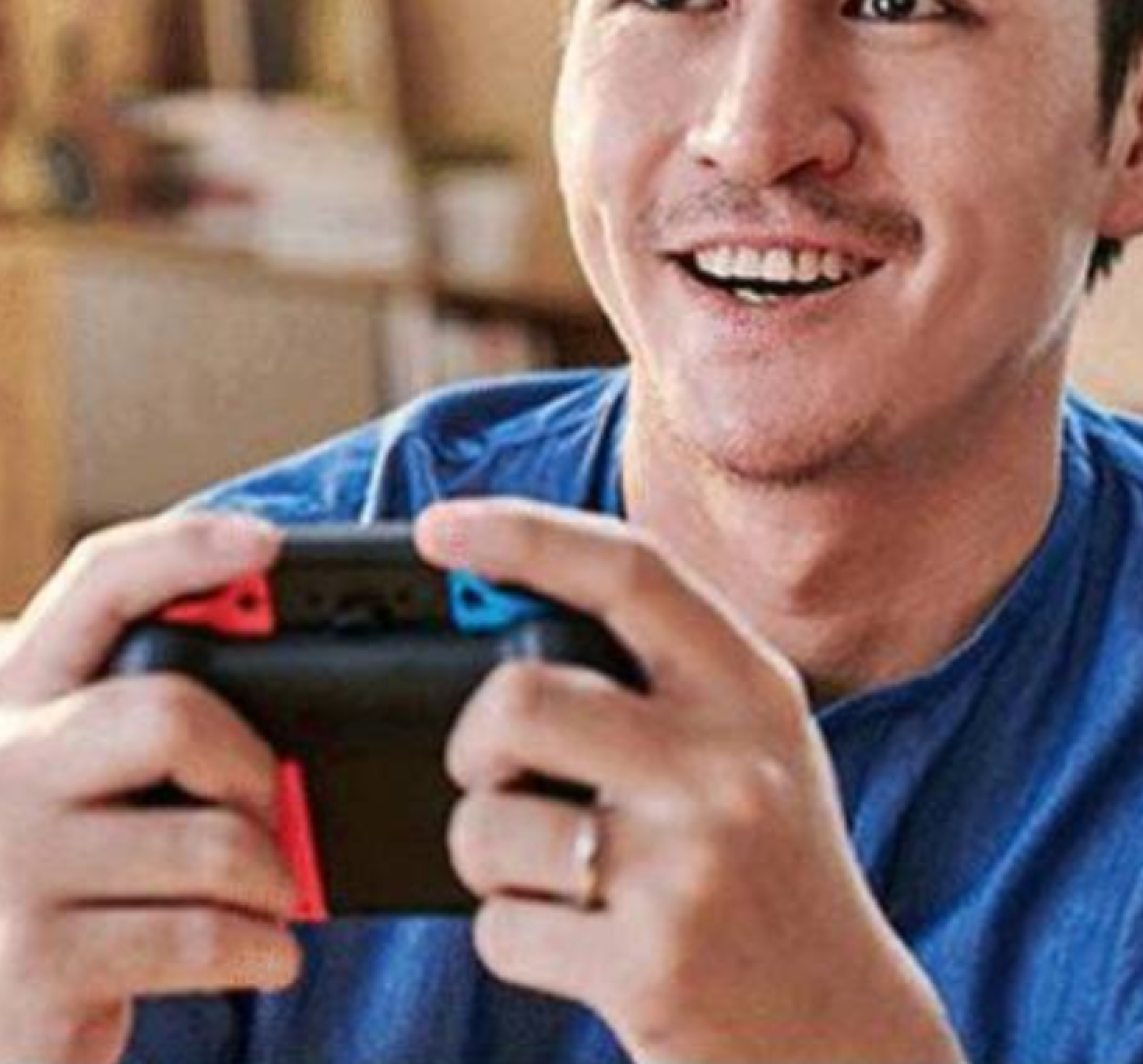Mann im blauen Hemd lächelt, während er einen Nintendo Switch hält.