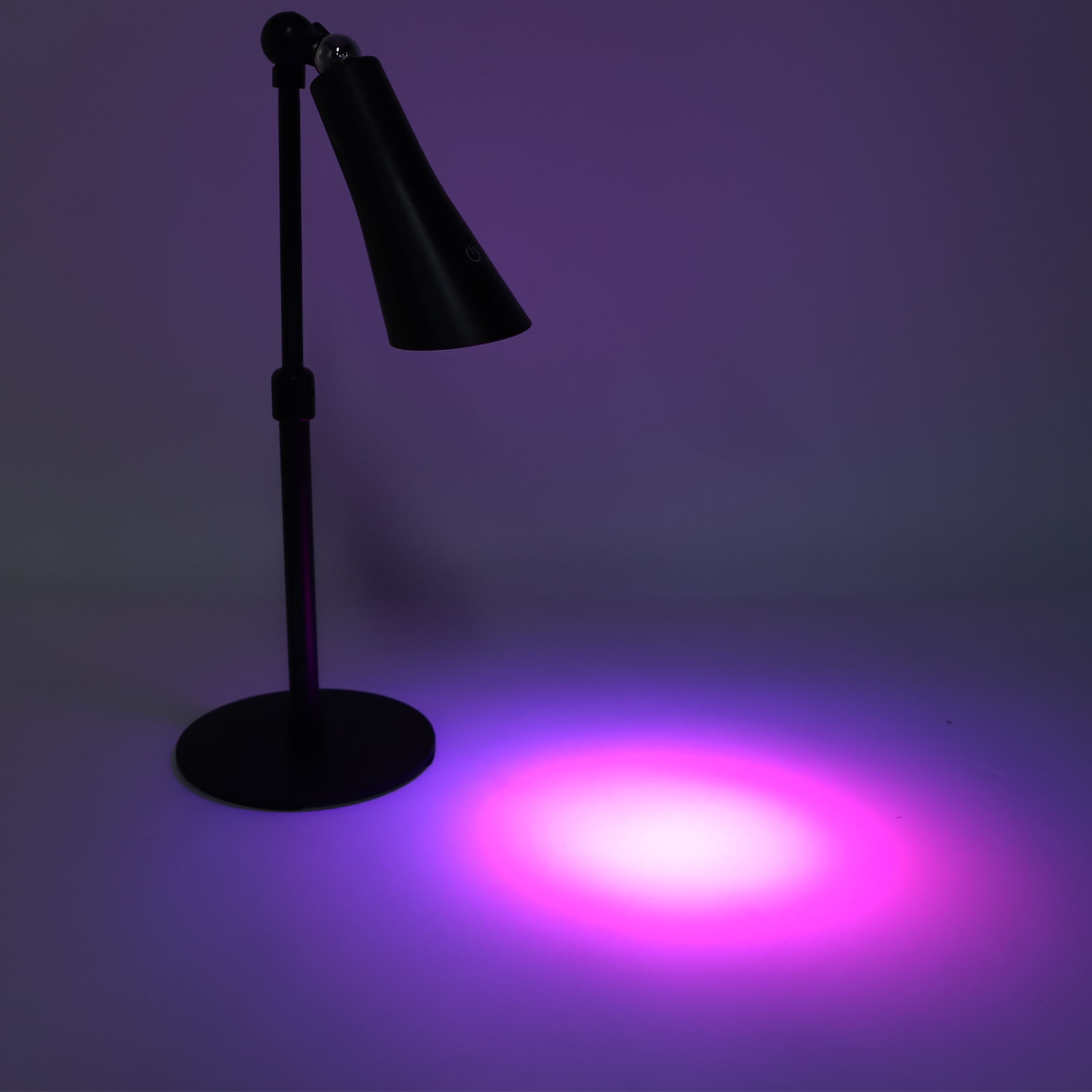 Schwarze Stehlampe beleuchtet Boden mit lila Licht.