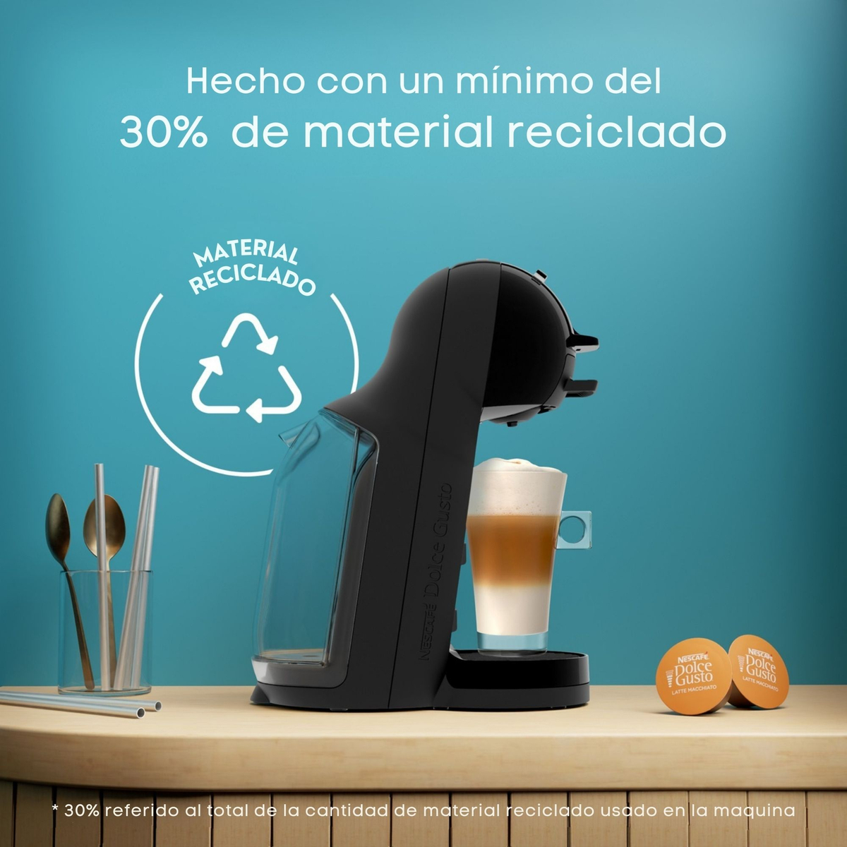 Schwarze Kaffeemaschine mit Milchkaffee und zwei Kapseln, Recycling-Symbol.