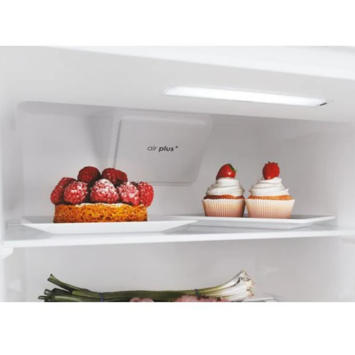 Una torta con lamponi e due cupcake con fragole all'interno di un frigorifero.