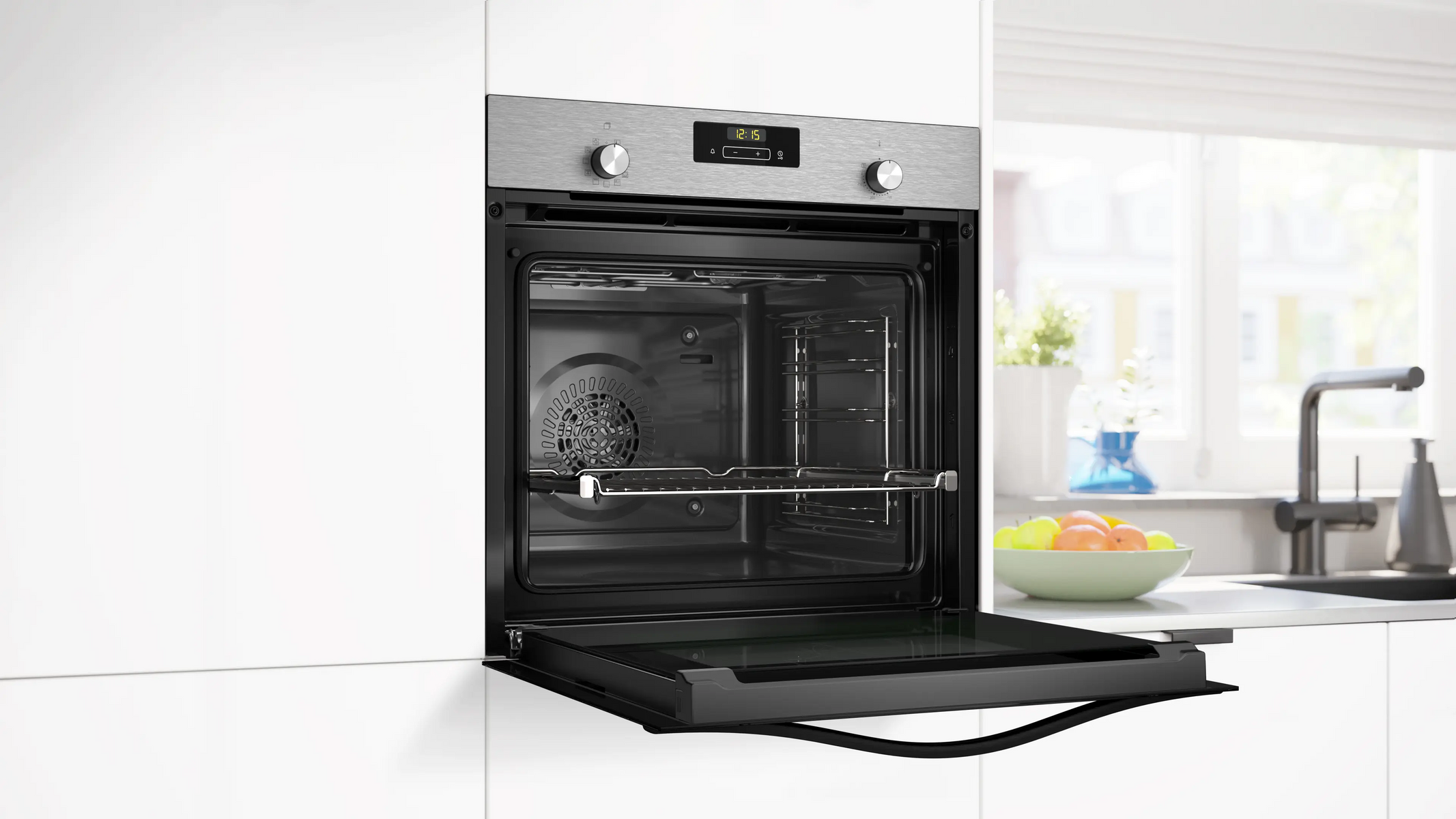 Forno da incasso moderno con porta aperta e display digitale. Ciotola di frutta sullo sfondo.