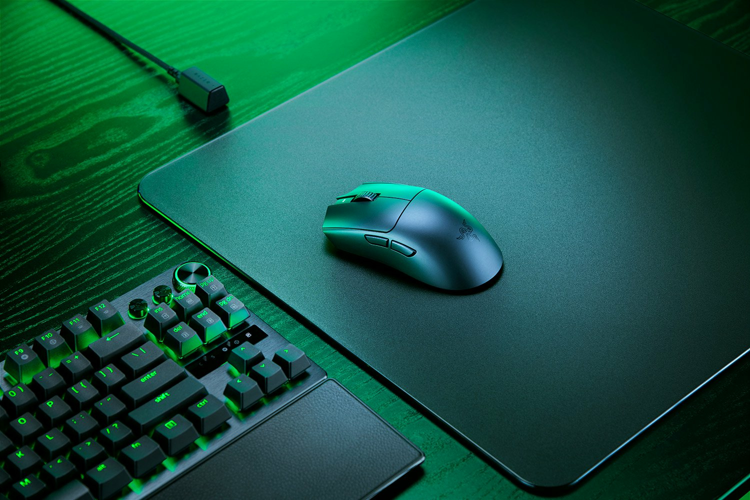 Un mouse e una tastiera da gaming verdi riposano su una scrivania di legno.