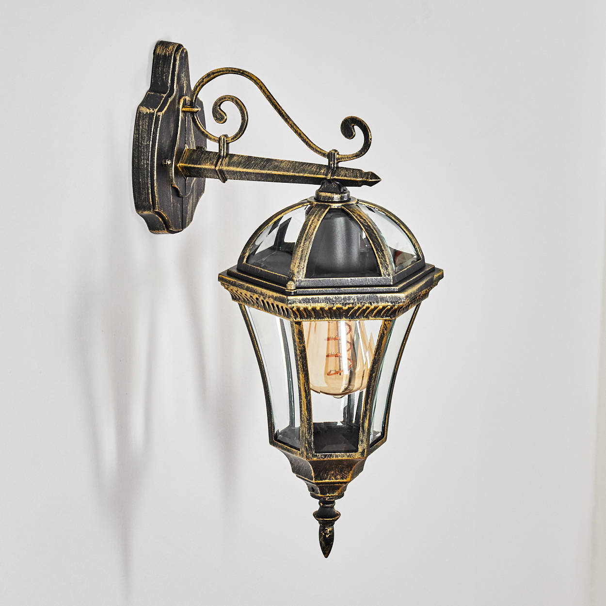Eine Wandlaterne im Vintage-Stil mit schwarzem und goldenem Metall, Glasscheiben und Edison-Glühbirne.