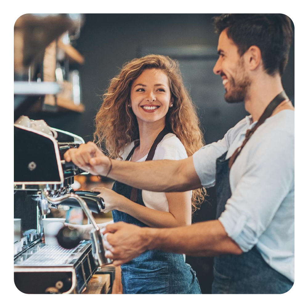 Ein Mann und eine Frau bedienen eine Espressomaschine in einem Café.