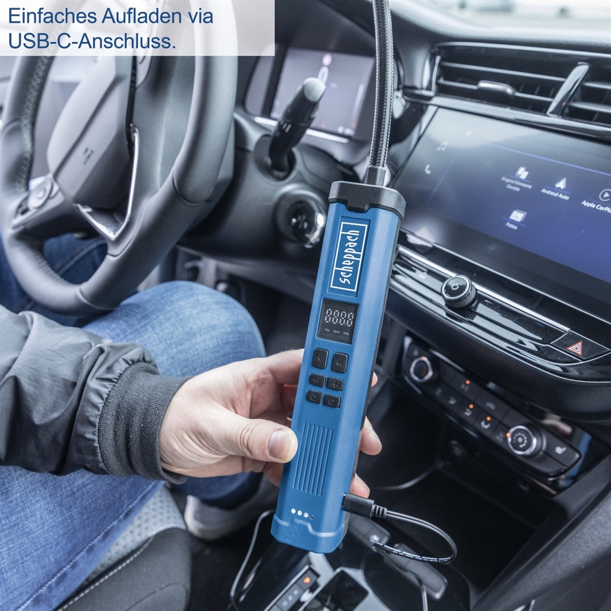 Person lädt ein blaues Messgerät im Auto über USB-C auf.