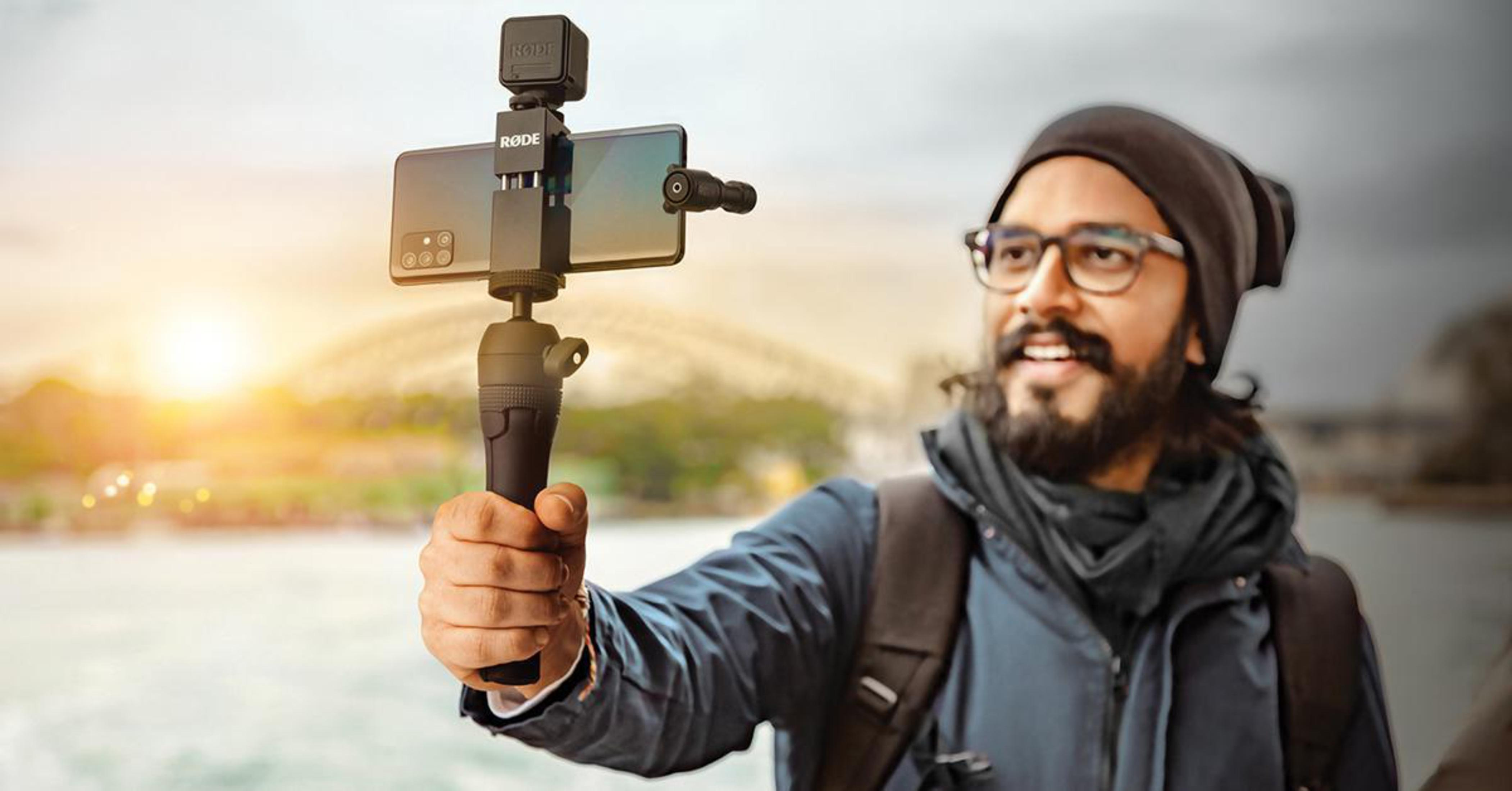 Un uomo con occhiali e barba filma con uno smartphone su un gimbal.