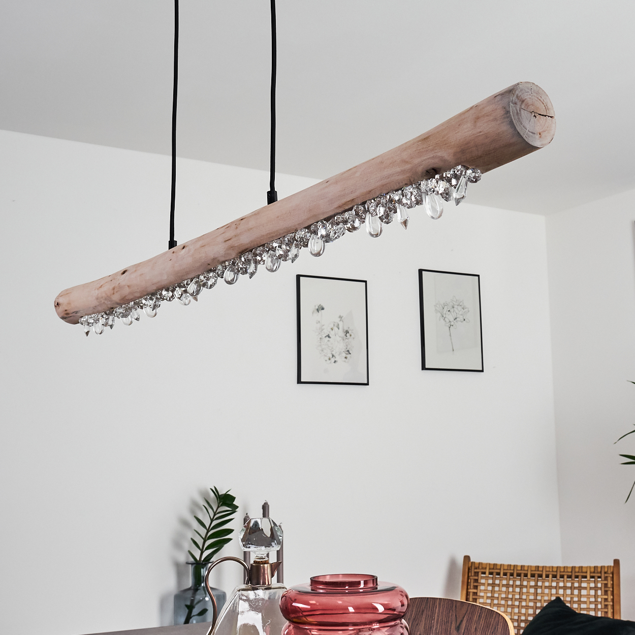 Ein rustikaler Kronleuchter aus Holz mit Kristallen hängt über einem Tisch mit Dekorationsgegenständen.
