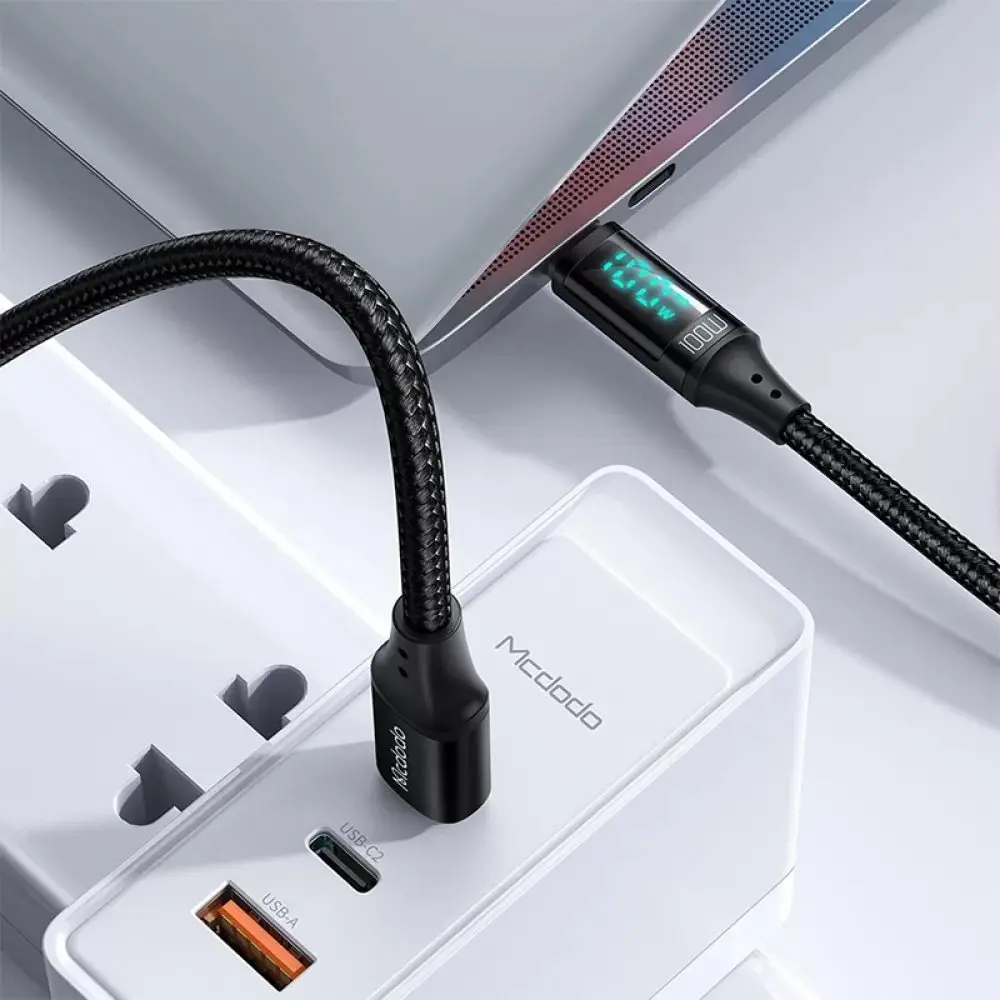 Siyah bir USB-C kablosu, beyaz bir güç adaptörüne bağlı dizüstü bilgisayarı şarj ediyor.