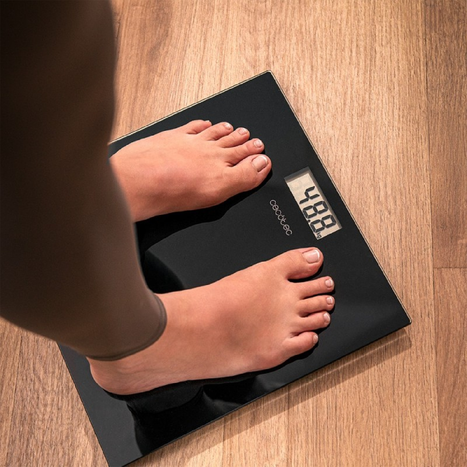 Stopy na czarnej wadze pokazującej 48,8 kg.