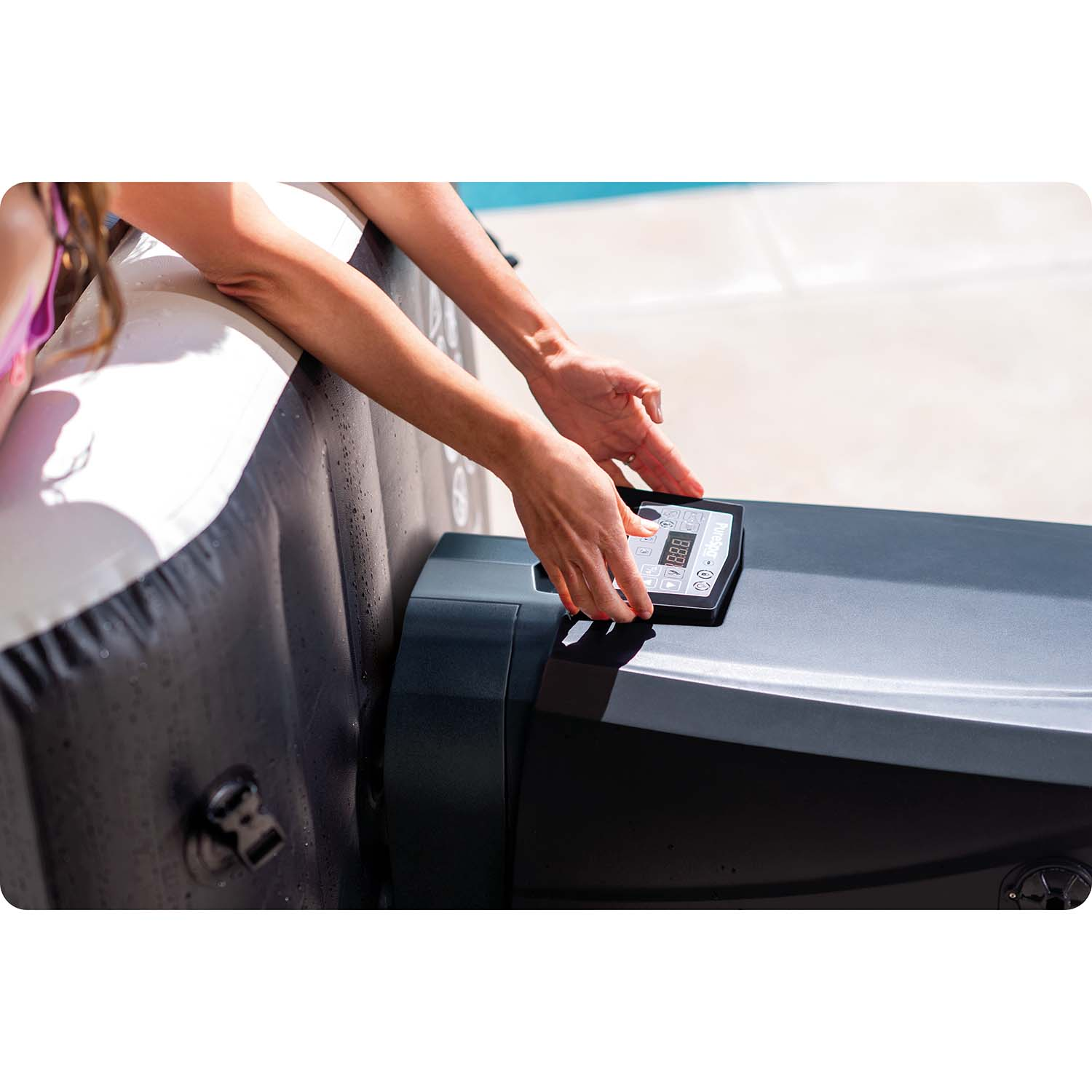 Eine Person bedient ein Bedienfeld an einem aufblasbaren Whirlpool neben einem Pool.