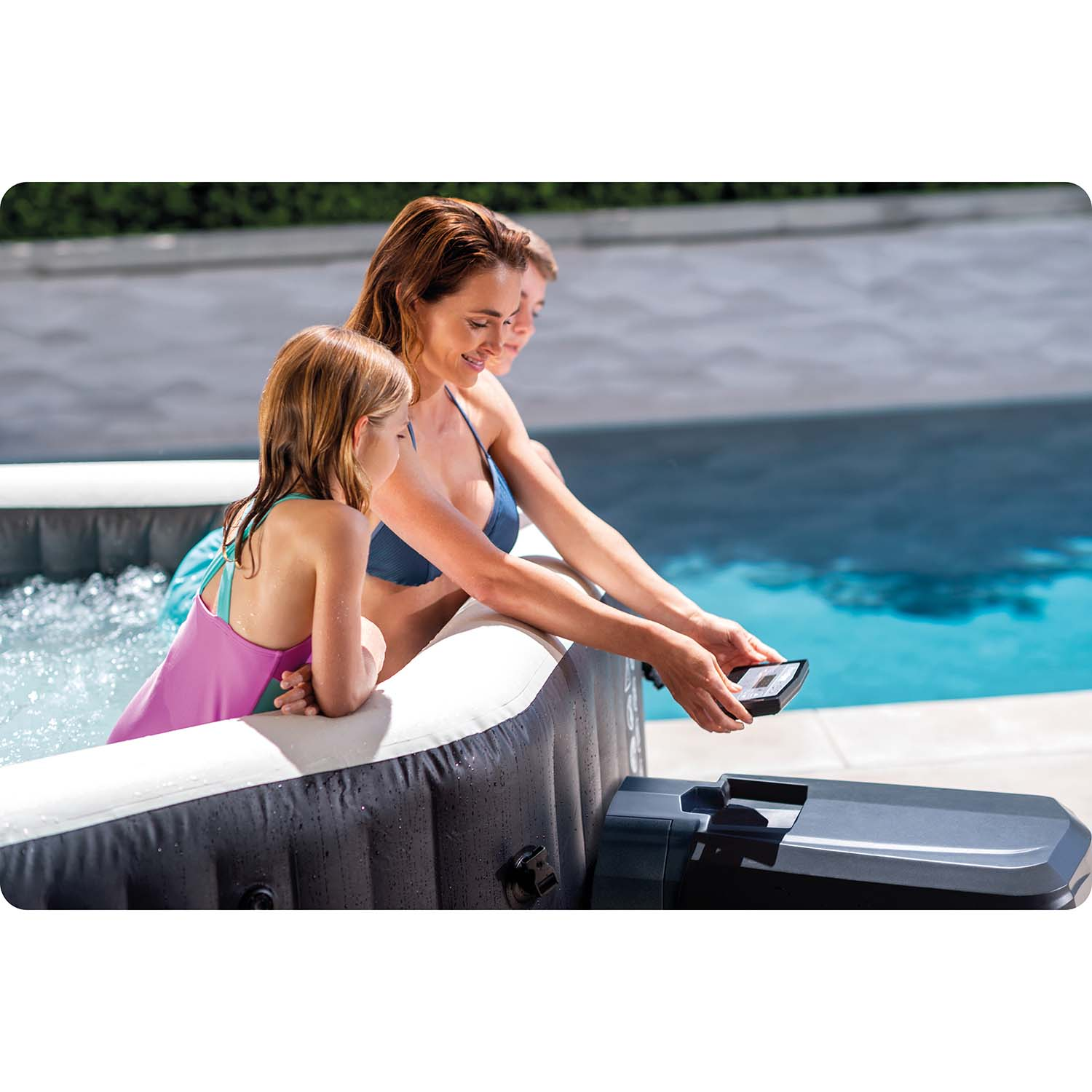 Frau bedient Steuerung eines Whirlpools mit zwei Kindern im Wasser.