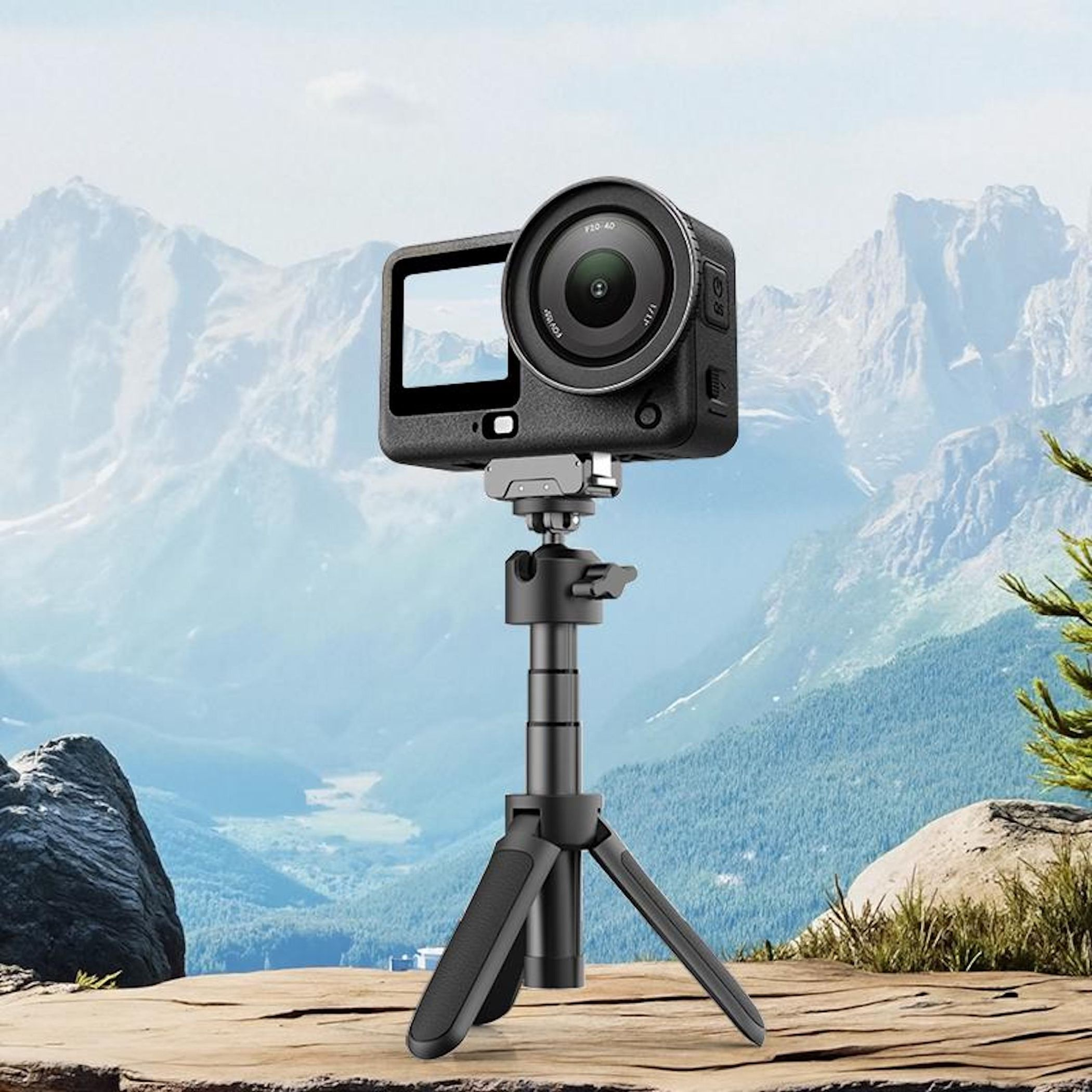 Action camera su treppiede su terreno roccioso con montagne e foresta sullo sfondo.
