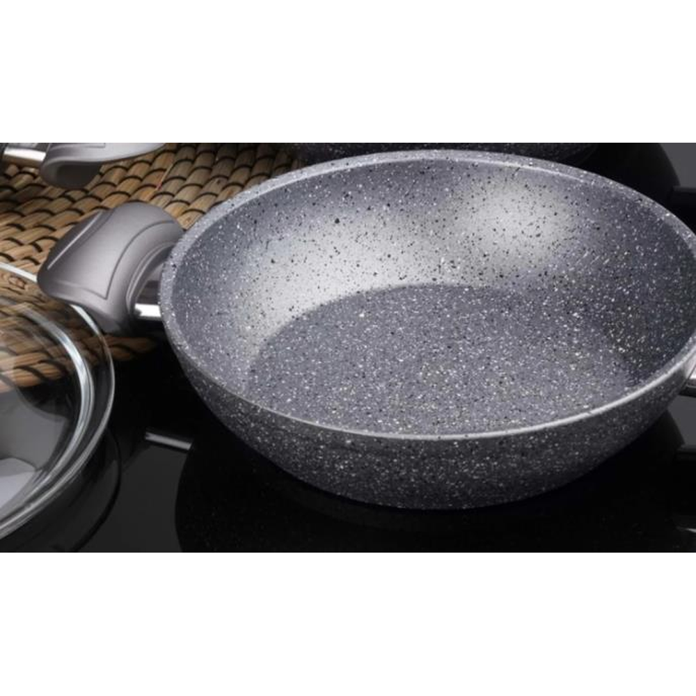 Gümüş saplı, gri benekli bir tava ve yakında cam kapak.