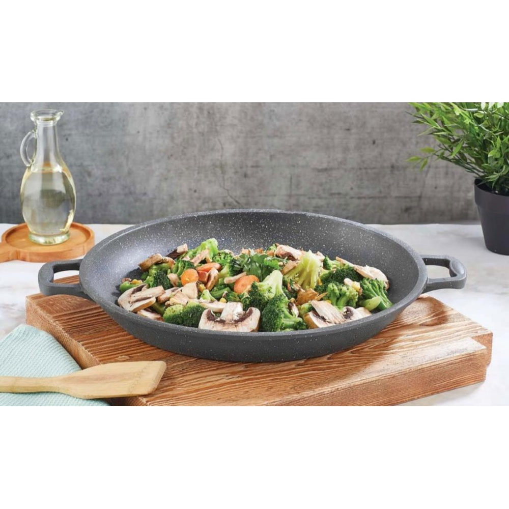 Gri bir wok, üzerinde brokoli, mantar ve havuç gibi karışık sebzelerle ahşap bir tahtada.