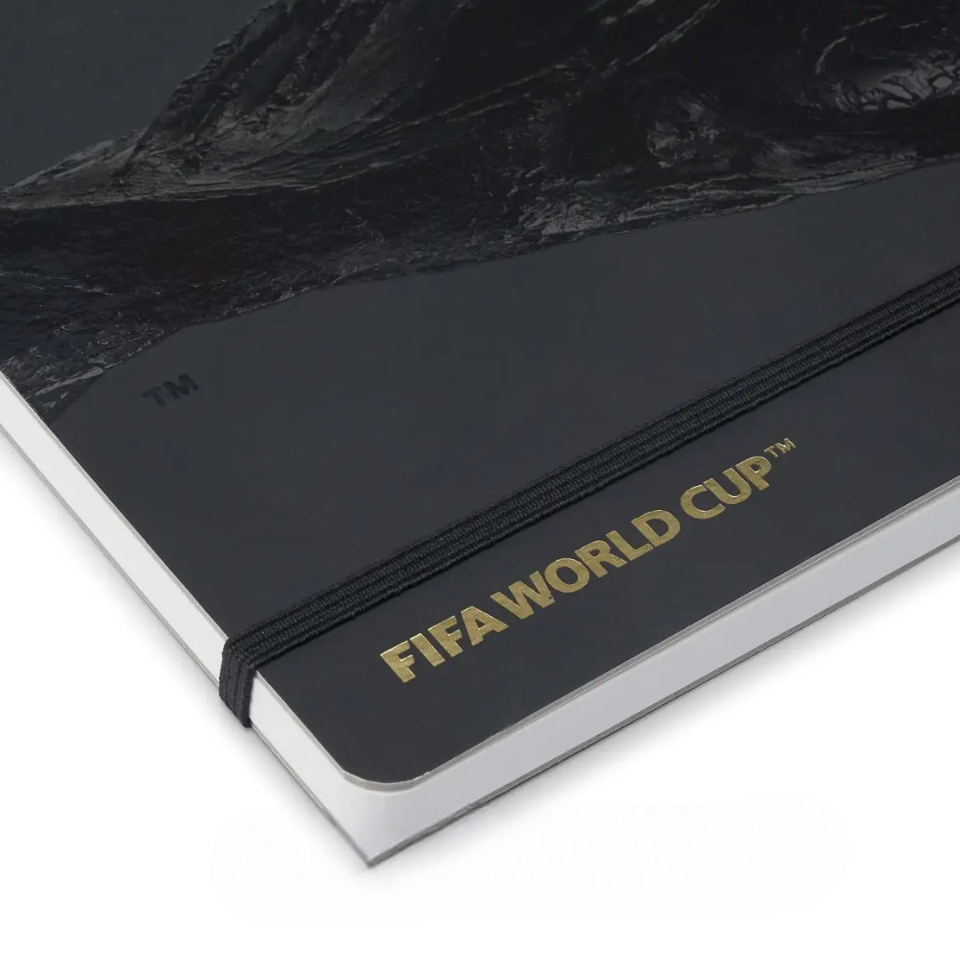 Schwarzes Notizbuch mit Goldprägung "FIFA WORLD CUP™" und Gummiband.