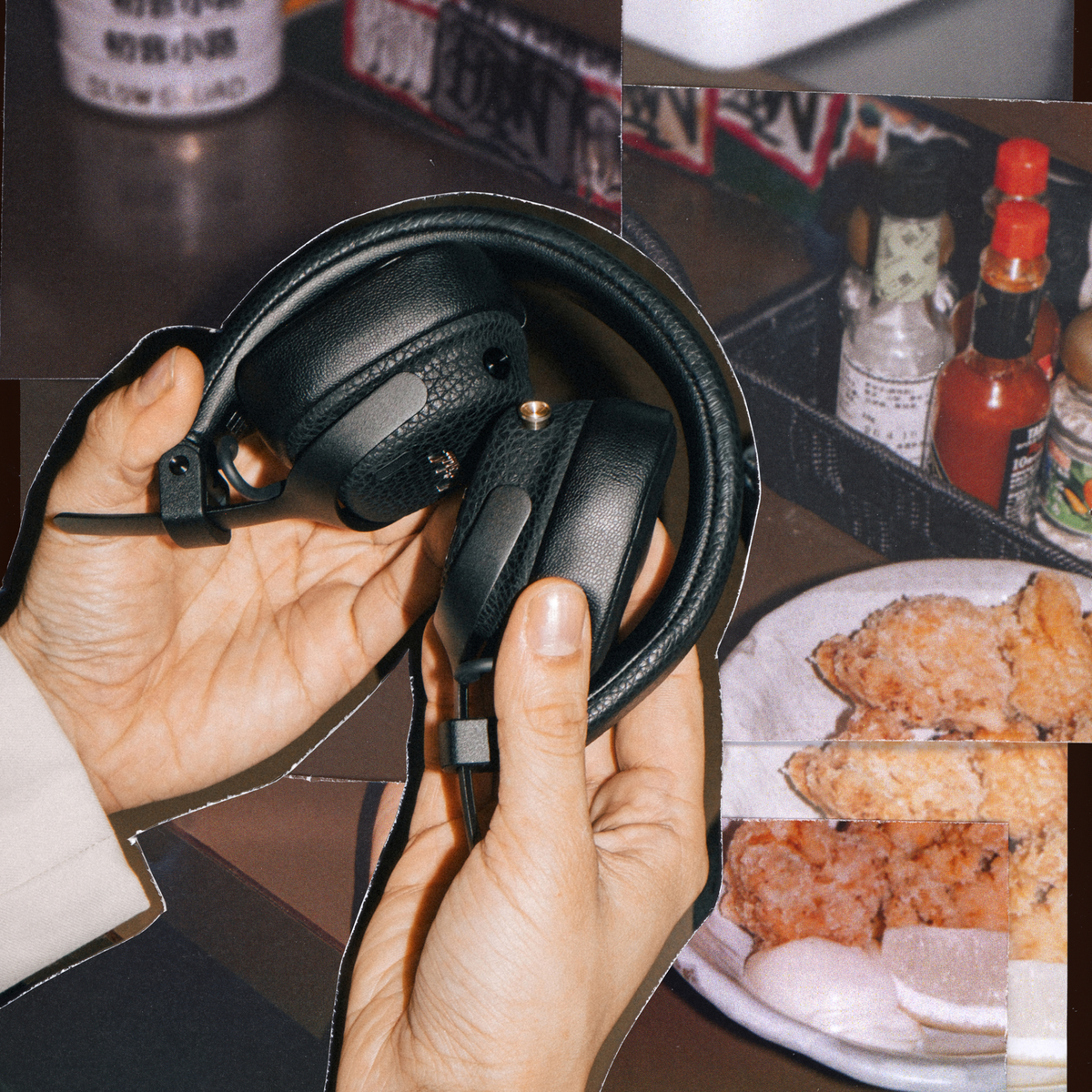 Schwarze Kopfhörer werden von Händen gehalten, daneben frittiertes Essen und Gewürzflaschen.