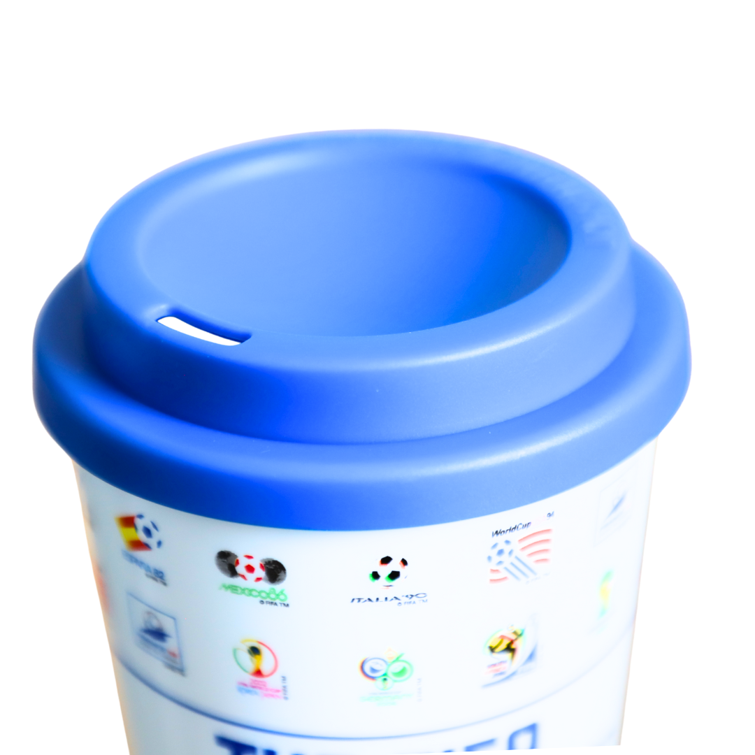 Weiße Tasse mit blauem Deckel, verziert mit Fußball-Logos wie WM und Italia 90.