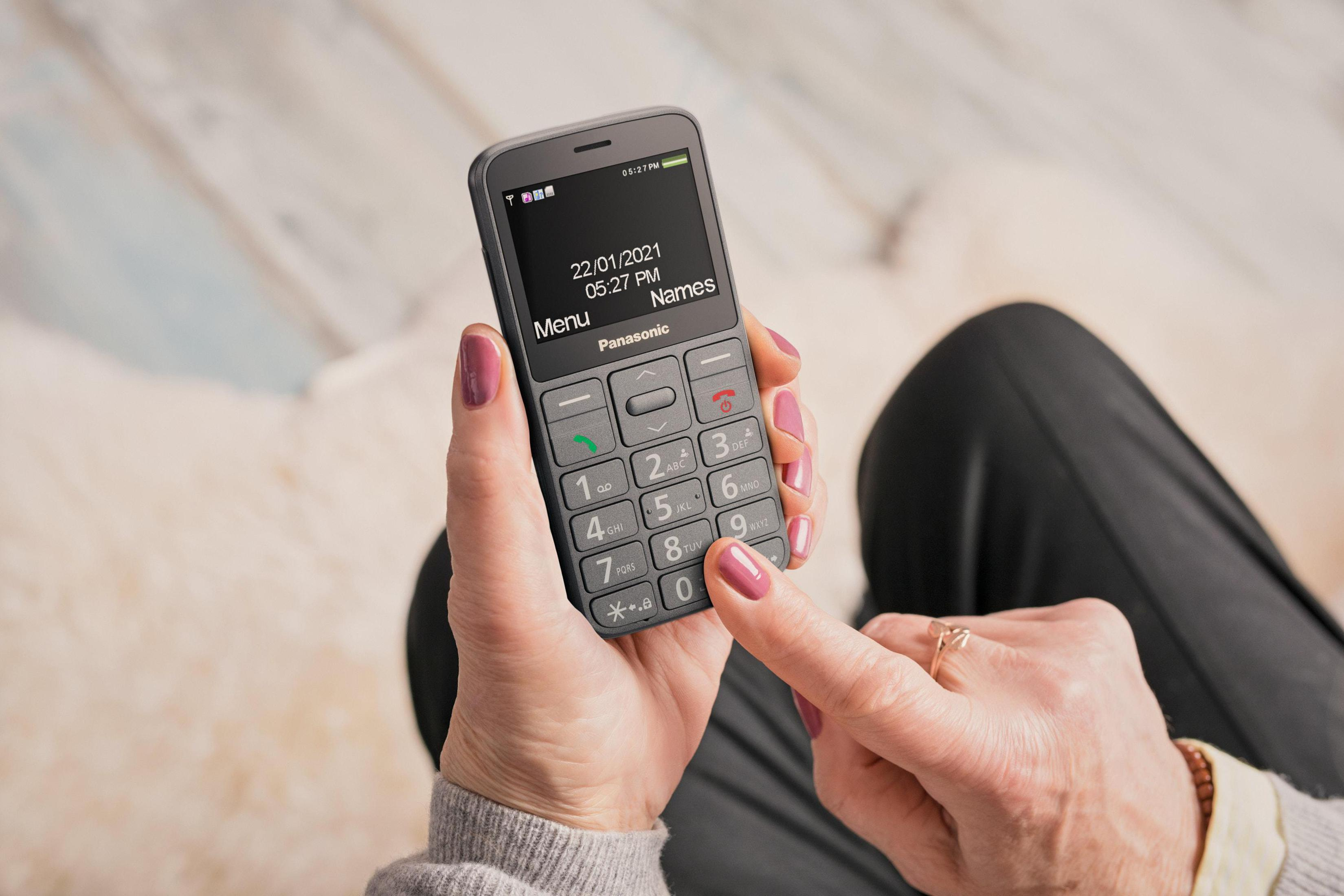 Eine Person hält ein Panasonic-Handy mit Tastatur und Display.