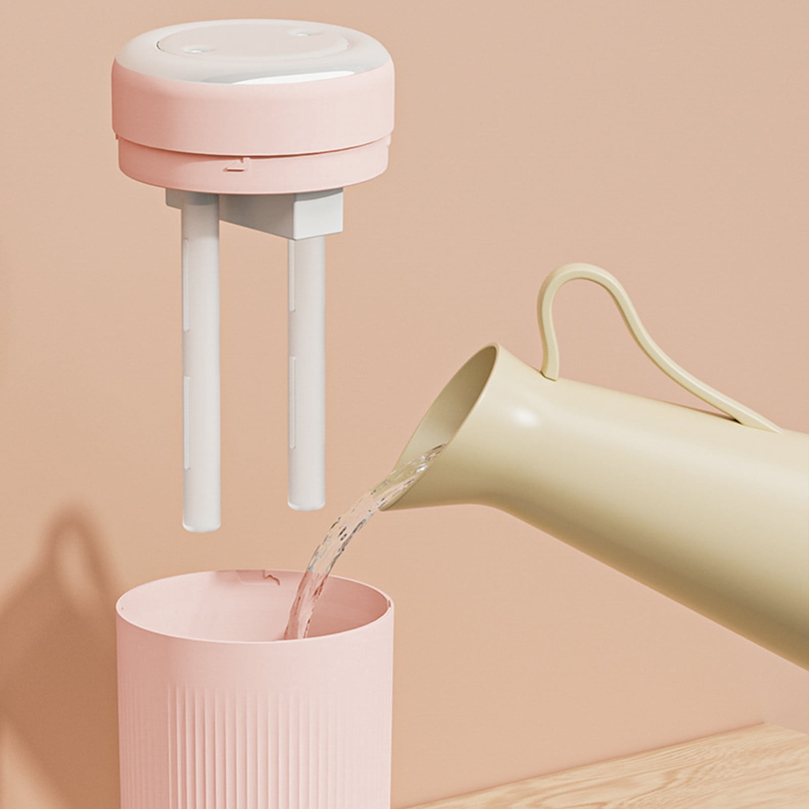 Ein beige Gießkanne gießt Wasser in einen rosa Behälter.