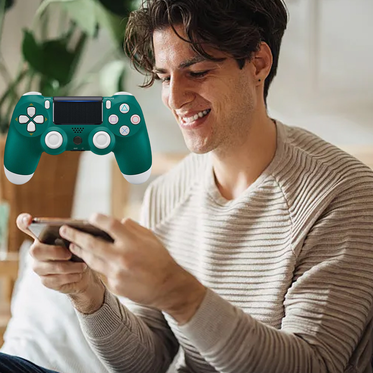 Mann lächelt, hält Handy, grüner Gamecontroller schwebt davor.