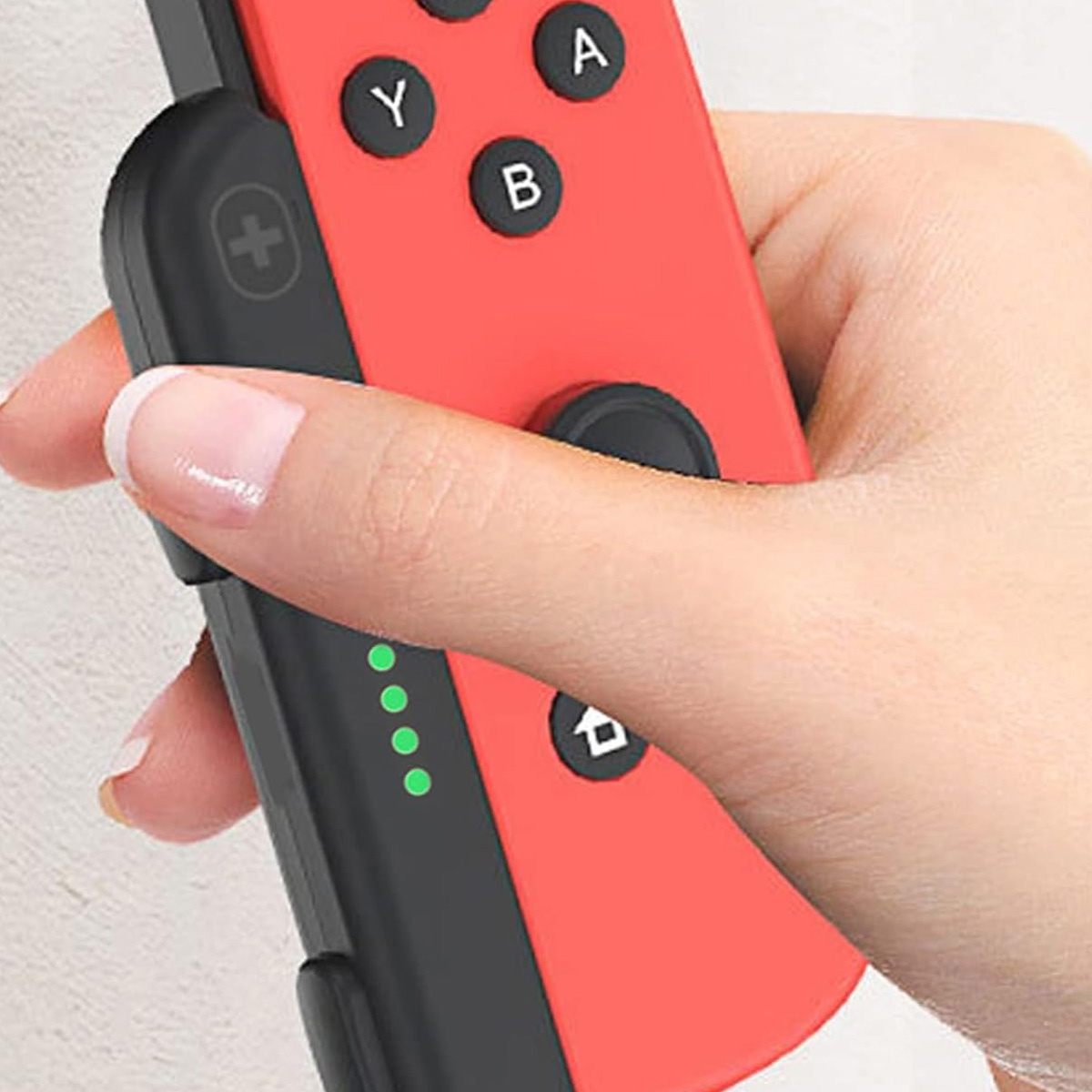 Eine Hand hält einen roten Joy-Con Controller mit A-, B-, Y-Tasten und vier grünen LEDs.