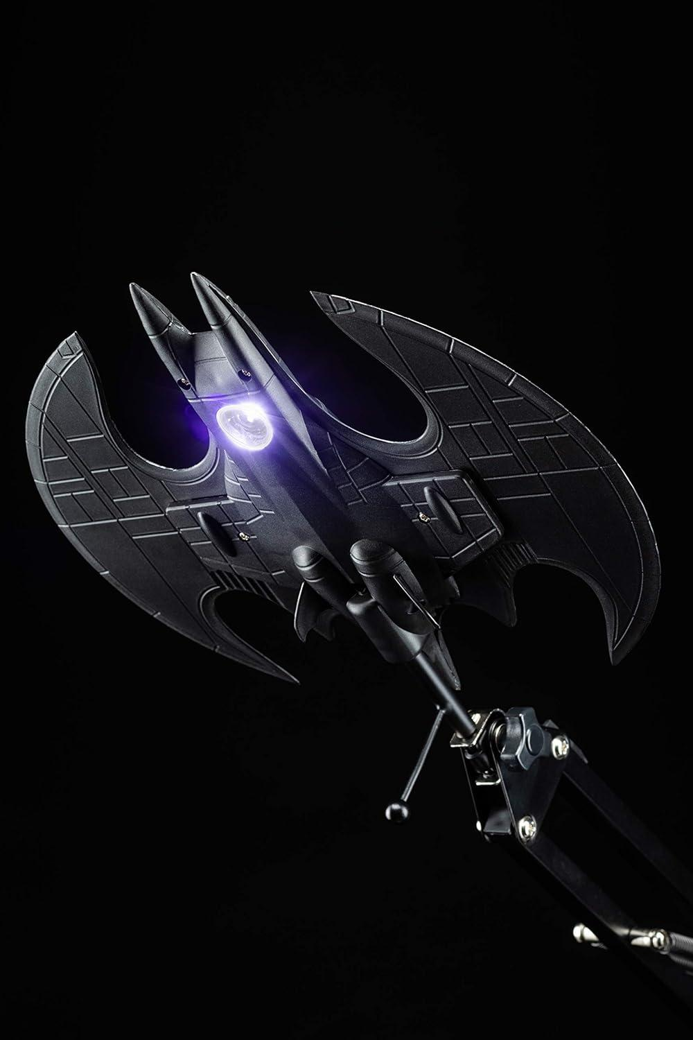Ein schwarzer Bat-Signal-Lampenaufsatz mit ausgestreckten Flügeln, beleuchtet mit einem violetten Schein.