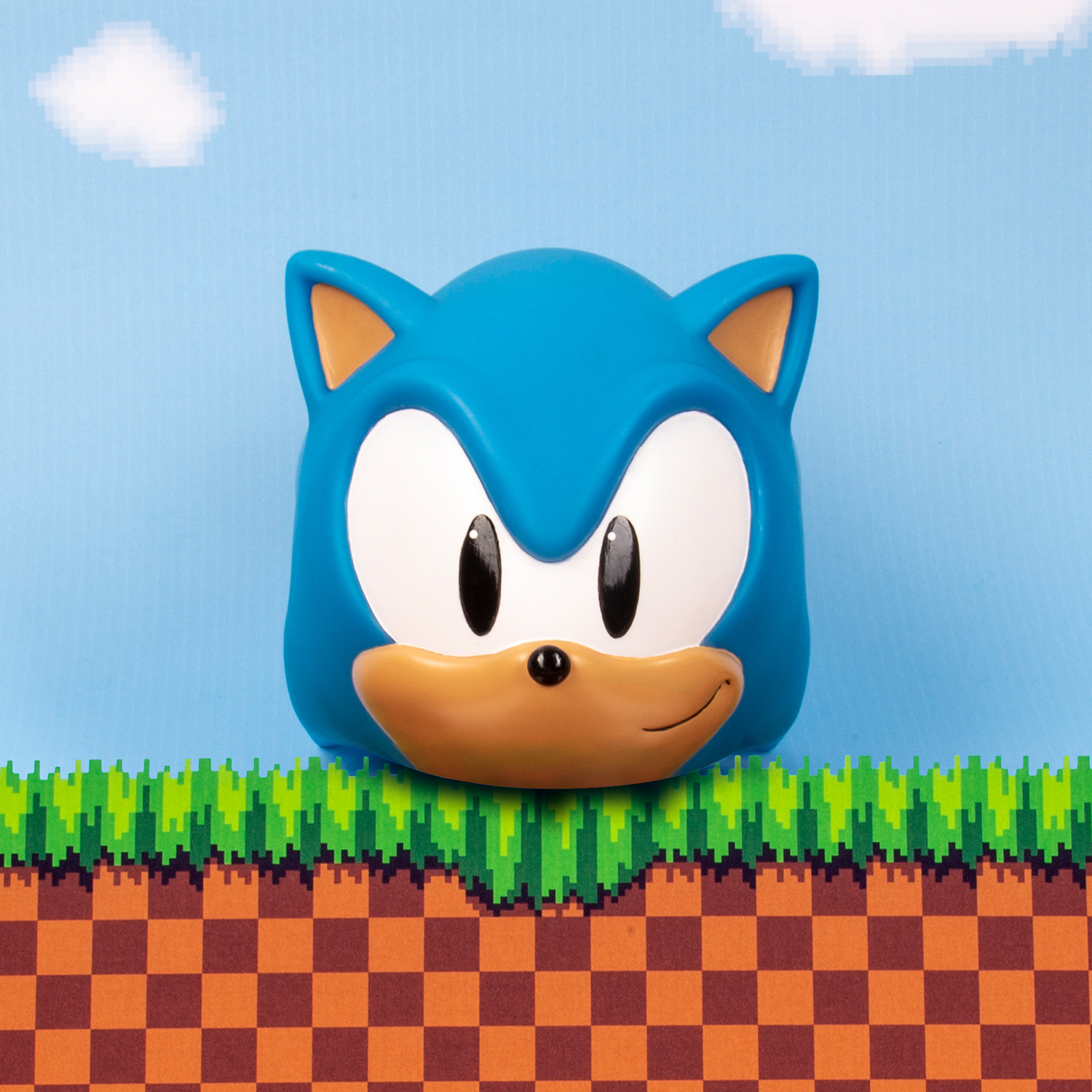 Sonic the Hedgehog's blue head with large eyes against a pixelated sky and grass.