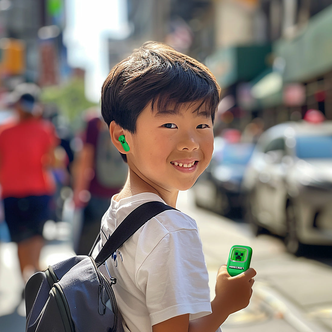 Een jongen met groene oordopjes en een Minecraft-hoesje lacht naar de camera.