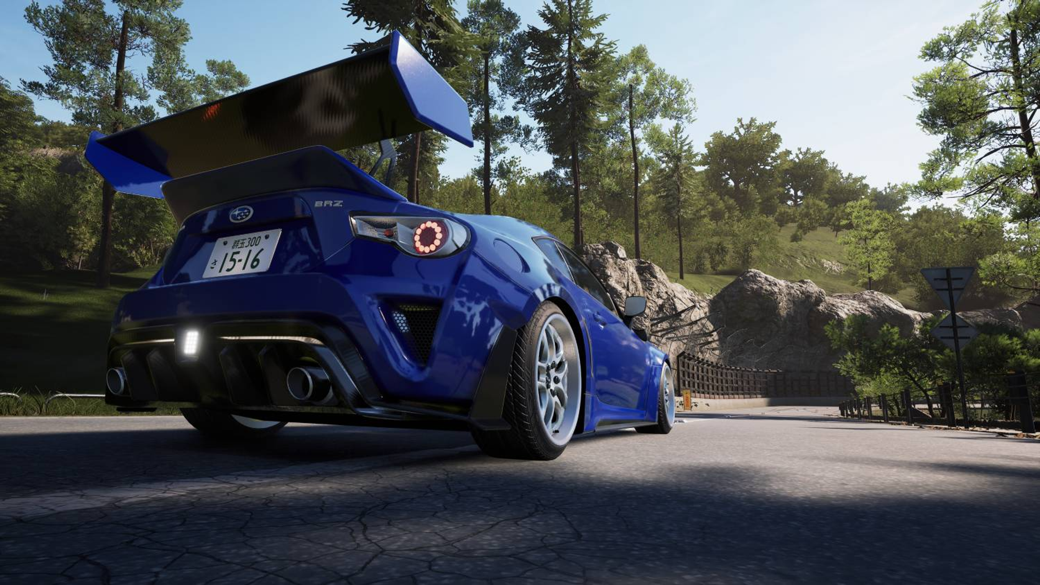 Subaru BRZ blu con grande spoiler posteriore su strada asfaltata nel bosco.