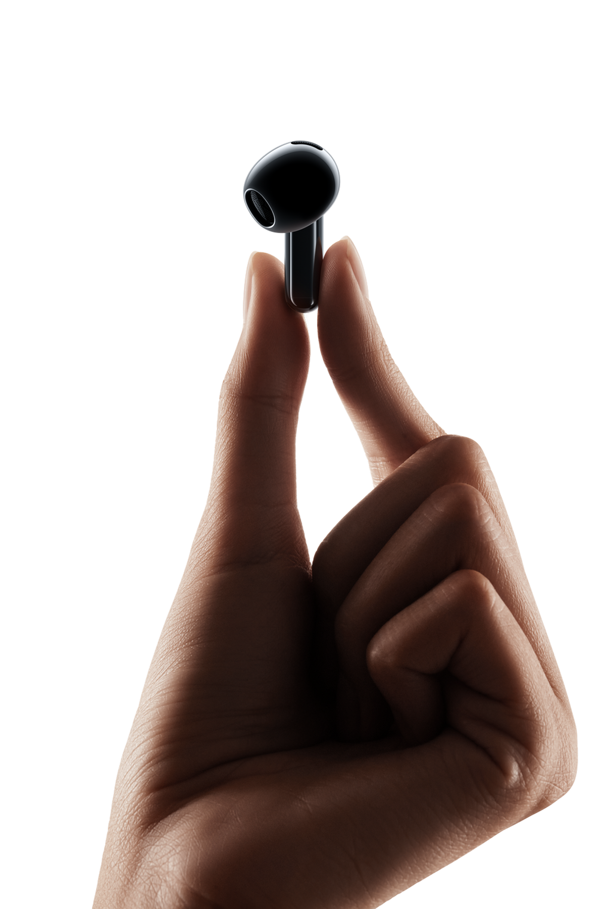 Una mano tiene un singolo auricolare wireless nero tra pollice e indice.