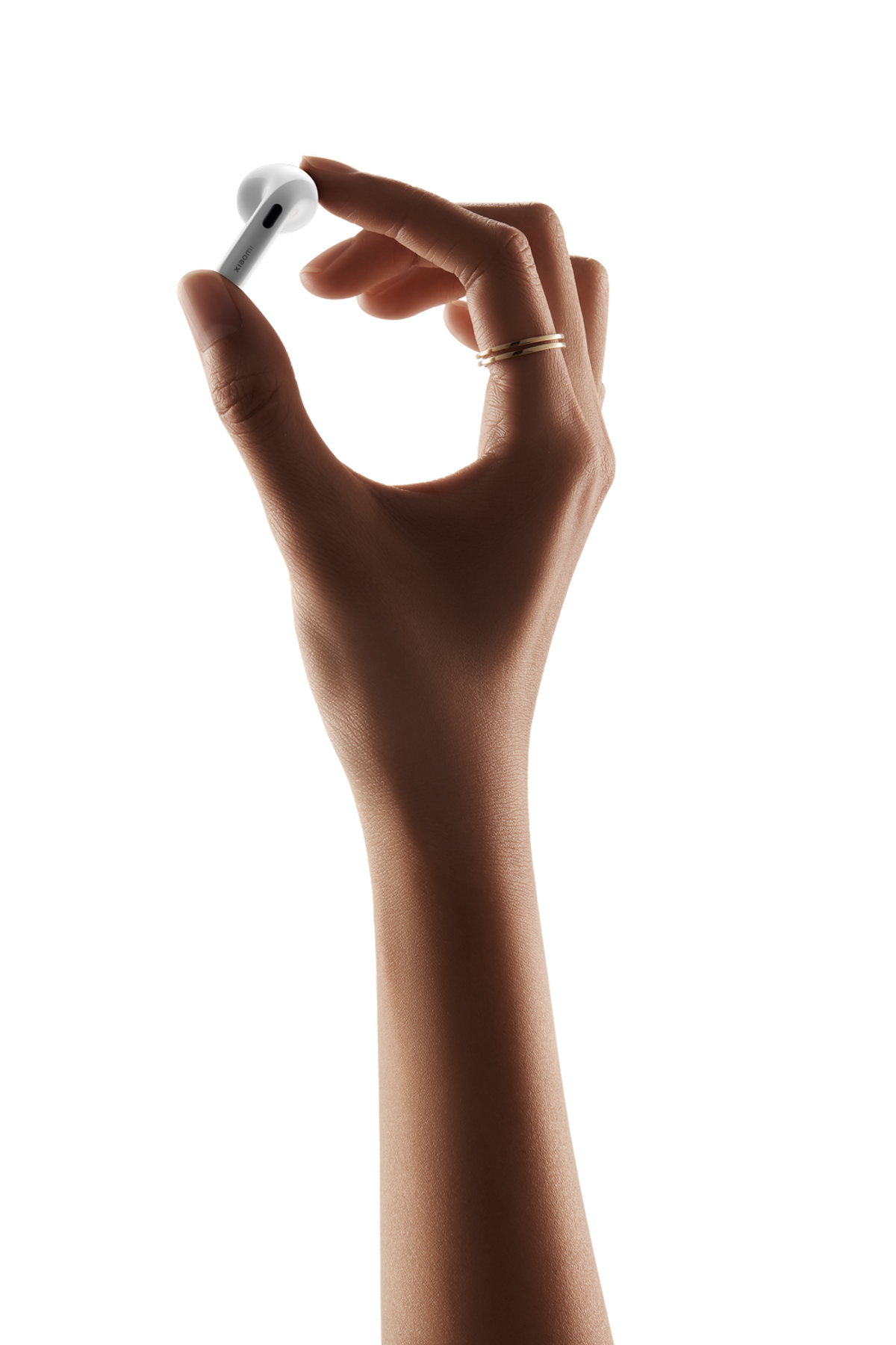 Eine Hand hält einen weißen Ohrhörer mit goldenen Ringen am Finger.
