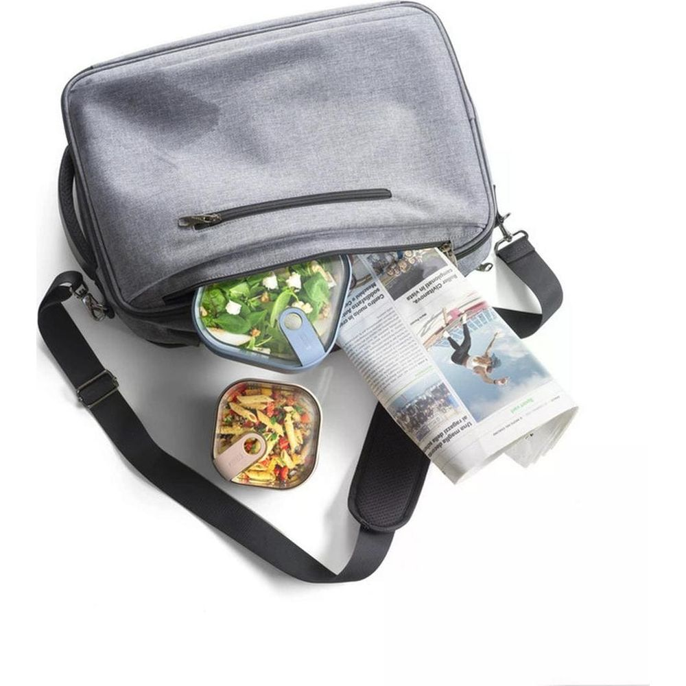 Borsa grigia con cibo e giornale. Una ciotola di insalata e una di pasta.